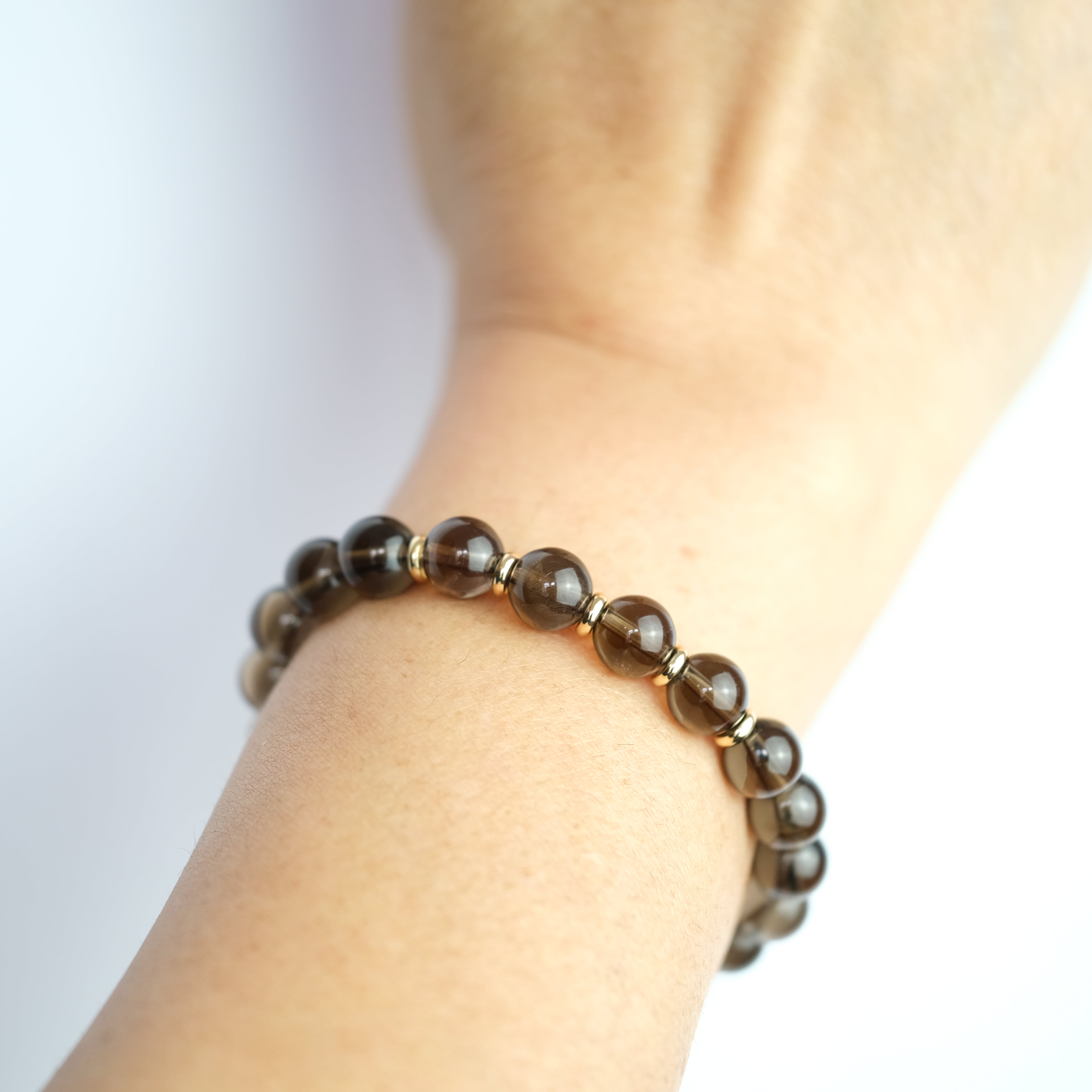 8mm Smoky Quartz Gemstone Bracelet with 18ct gold plated accessories on a models wrist 