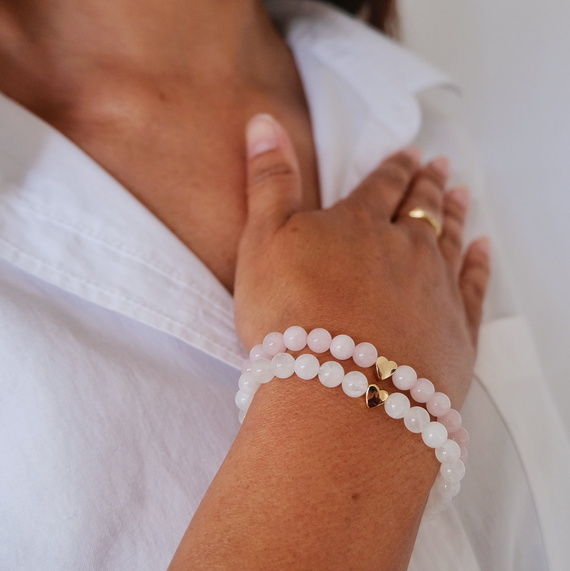 A model wearing a moonstone and rose quartz gemstone bracelet with gold love heart detail