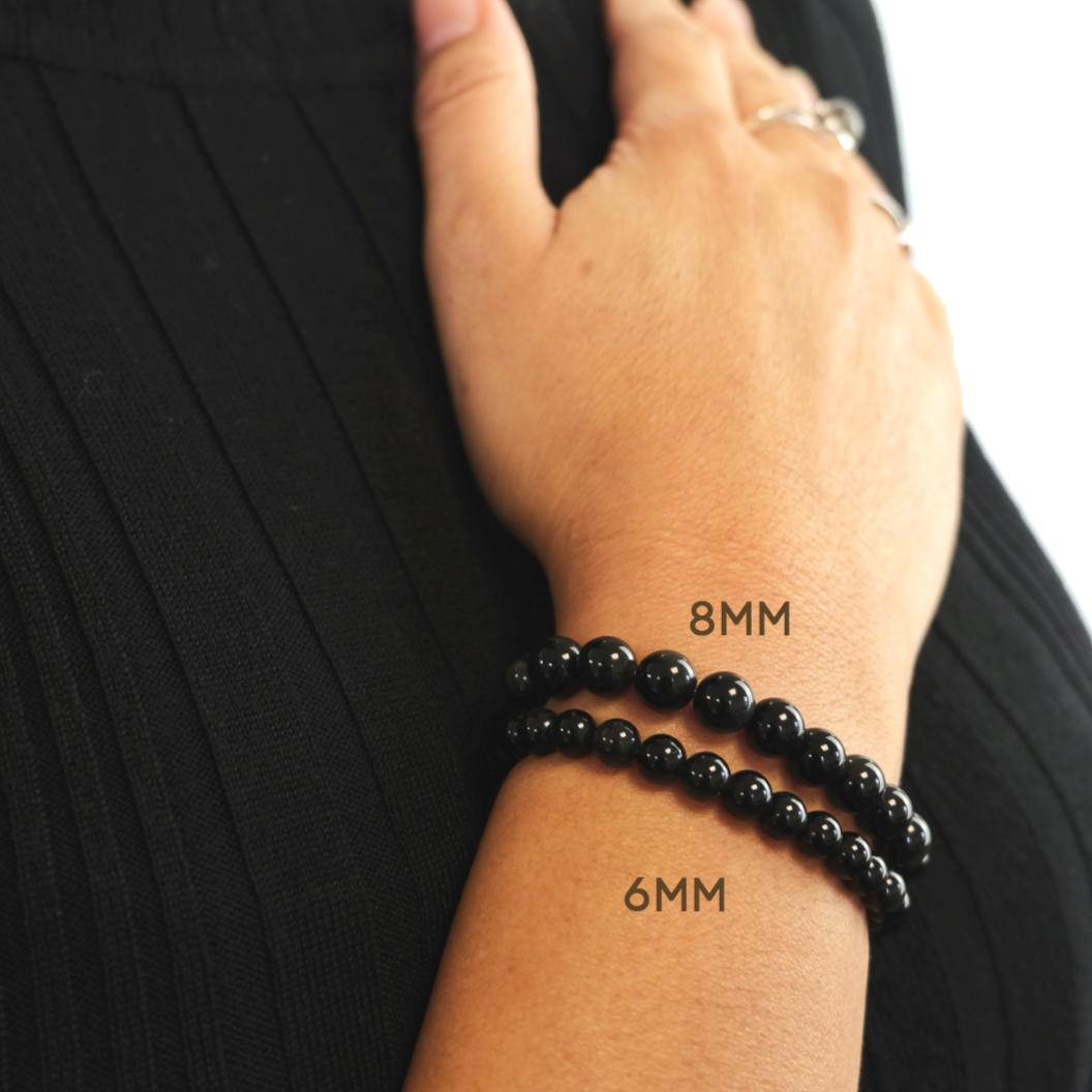 Black tourmaline gemstone bracelets in 6mm and 8mm bead size worn on a model's wrist