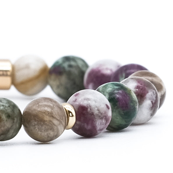 A close up of a tourmaline, silver leaf and green lepidolite gemstone bracelet with gold filled accessories