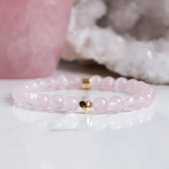 A rose quartz gemstone bracelet with gold love heart