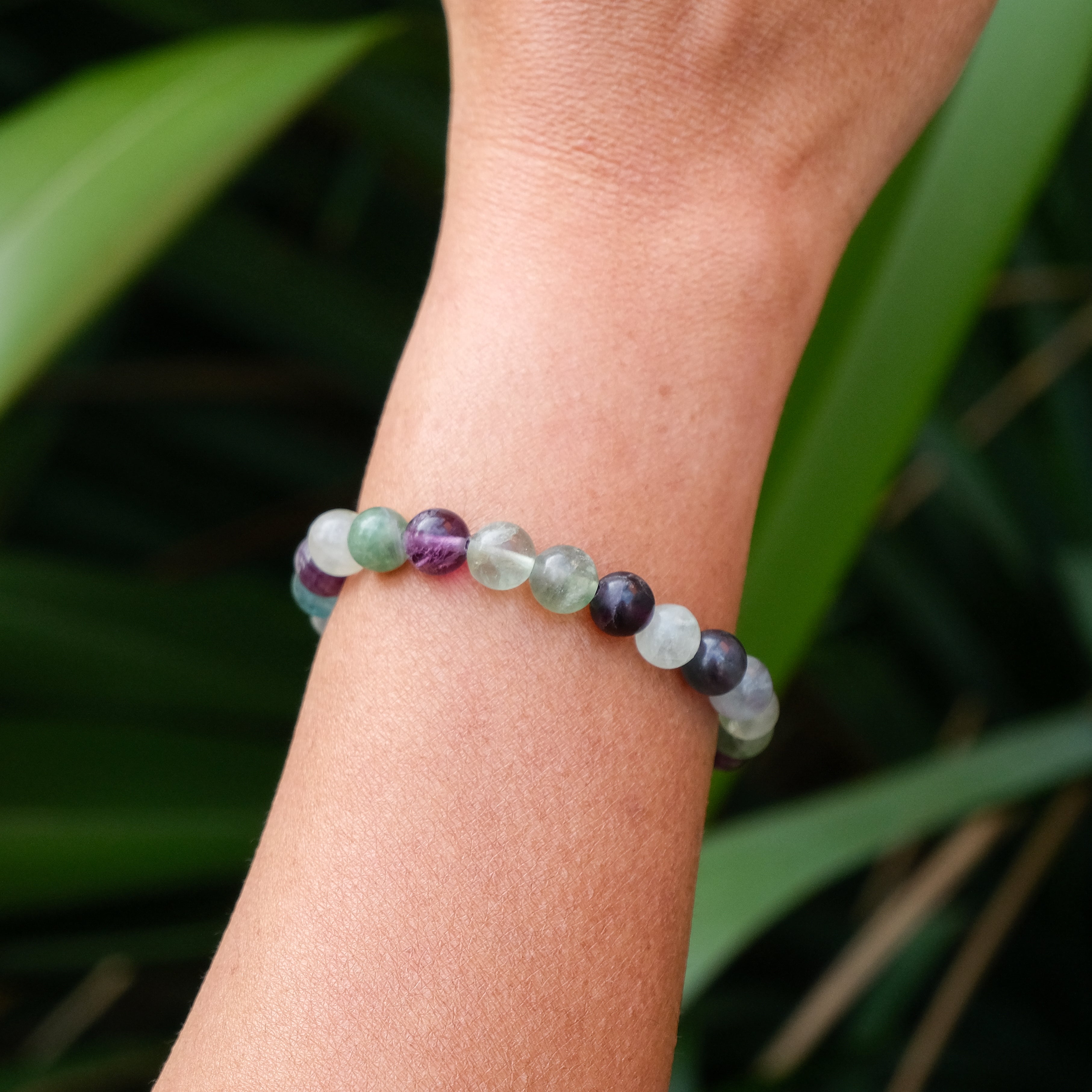 A fluorite gemstone bracelet worn on a model's wrist