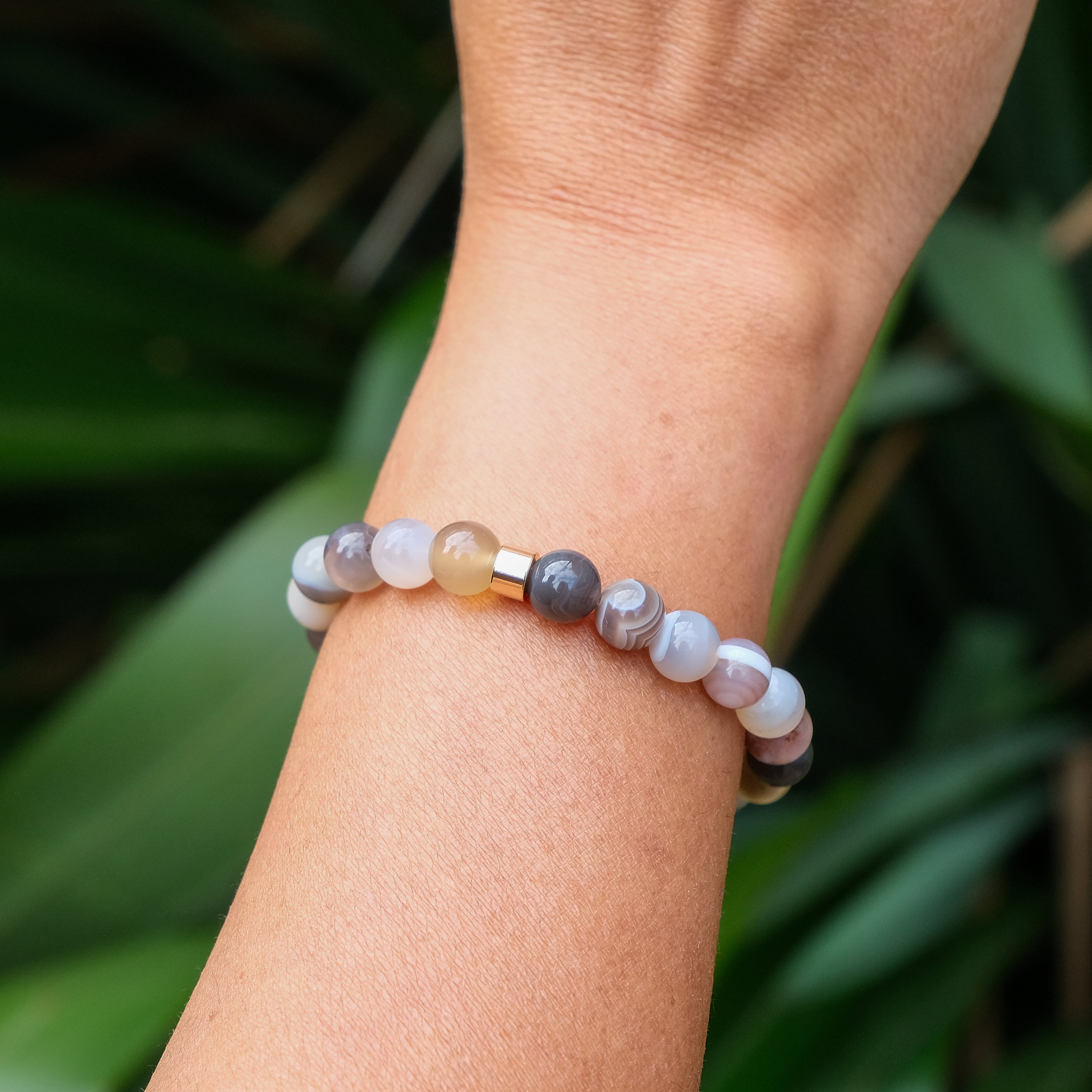 Botswana agate gemstone bracelet with gold accessory worn on a model's wrist