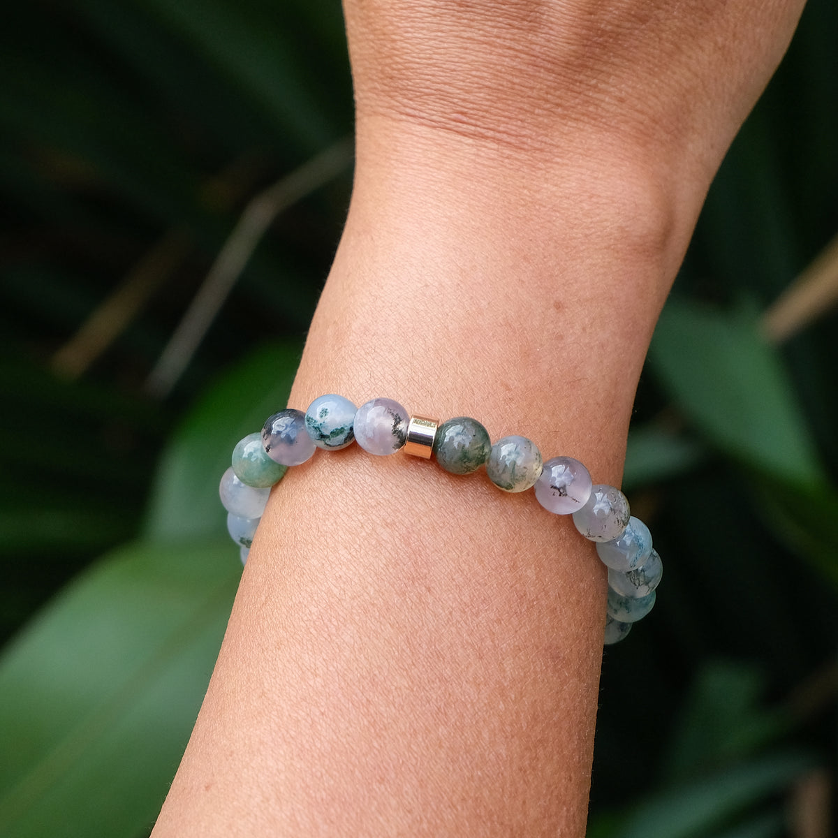The back of a moss agate gemstone bracelet with gold accessory worn by a model