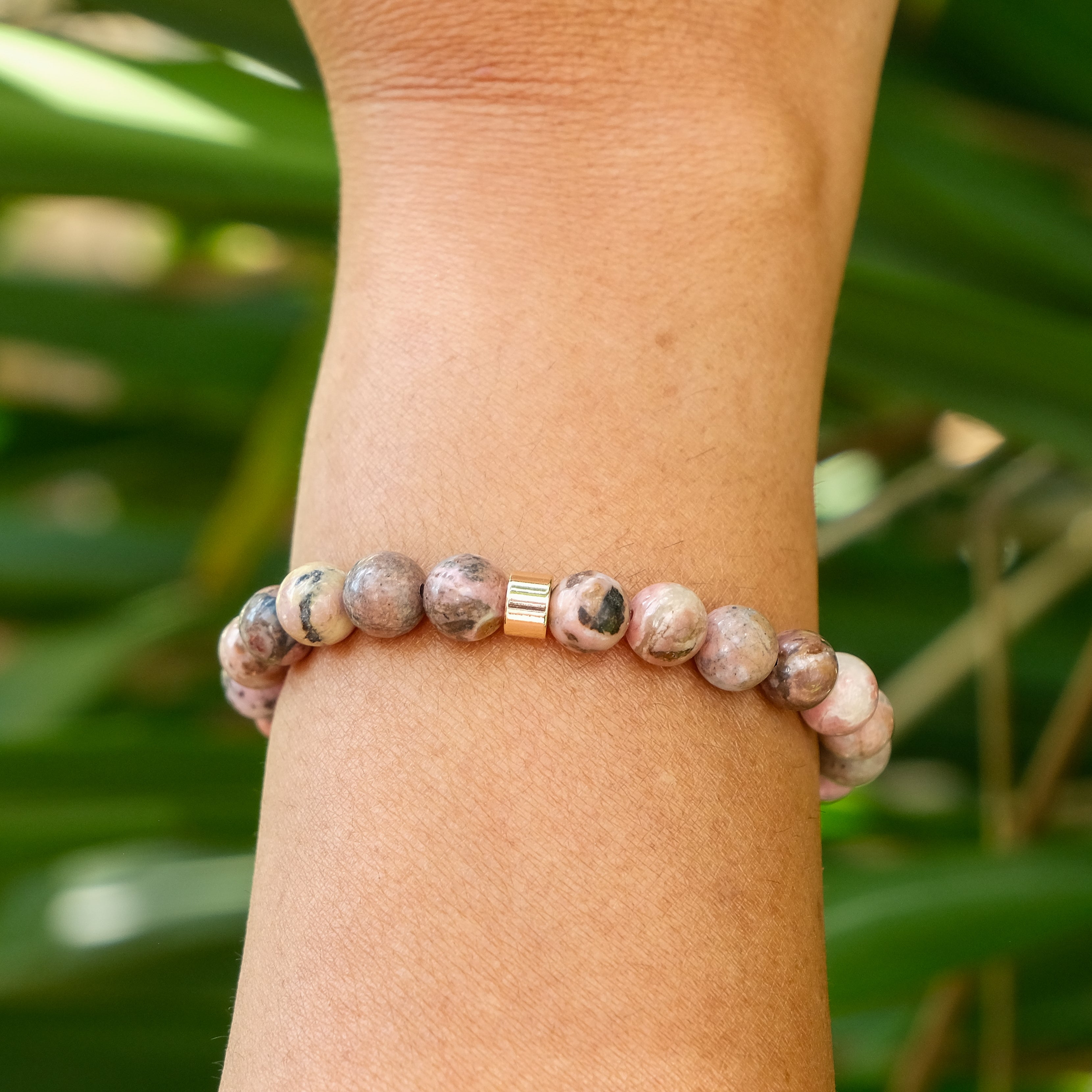 The back of A Rhodonite gemstone bracelet worn on a model's wrist