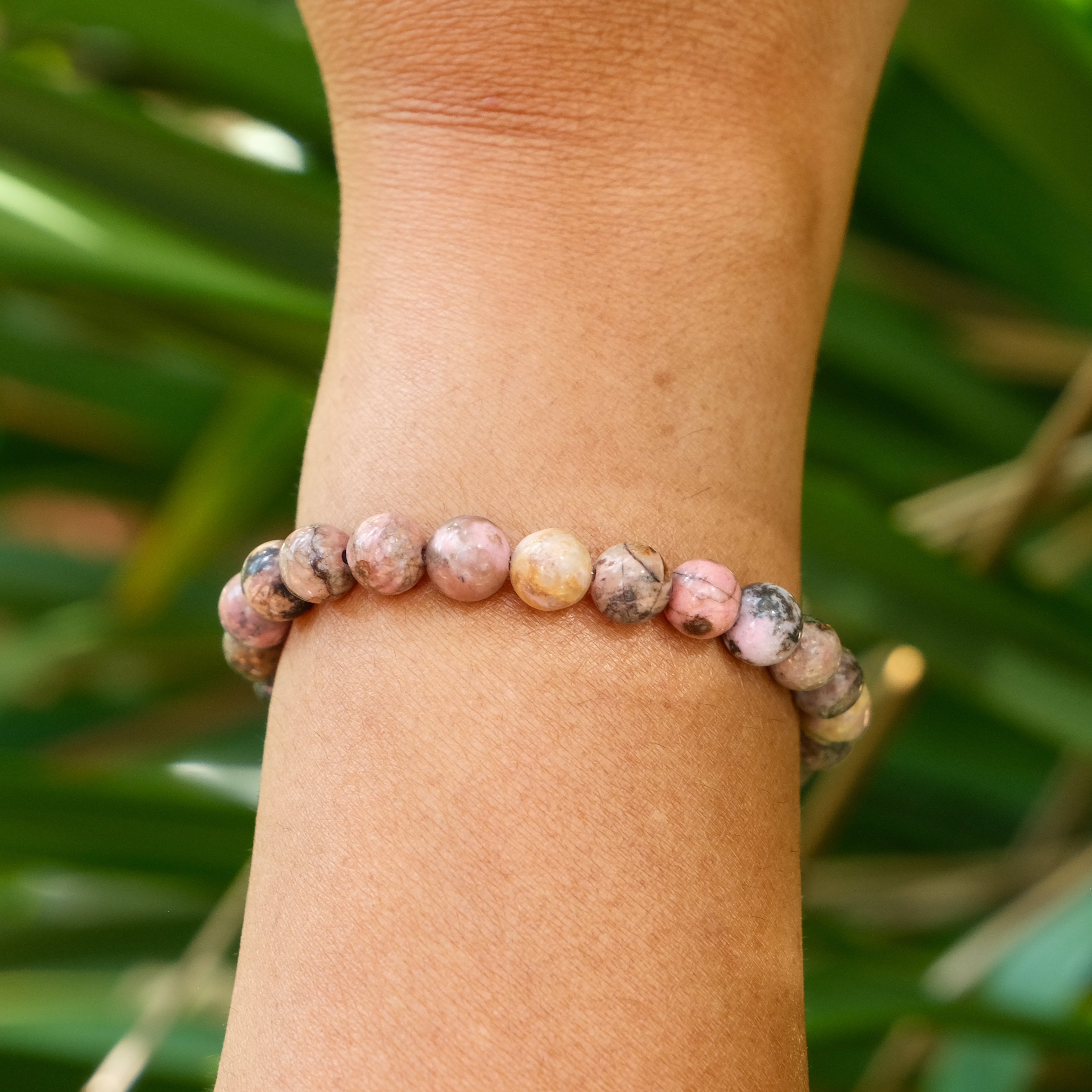 A Rhodonite gemstone bracelet worn on a model's wrist