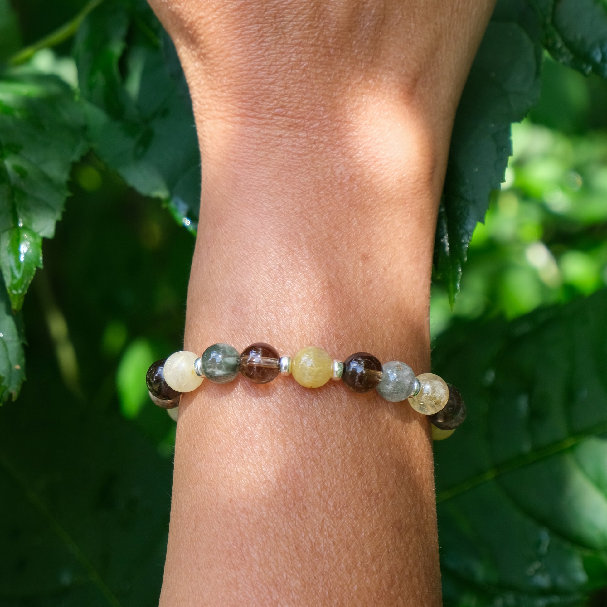 A model wearing a rutilated quartz, smoky quartz and green phantom quartz bracelet with gold filled accessories
