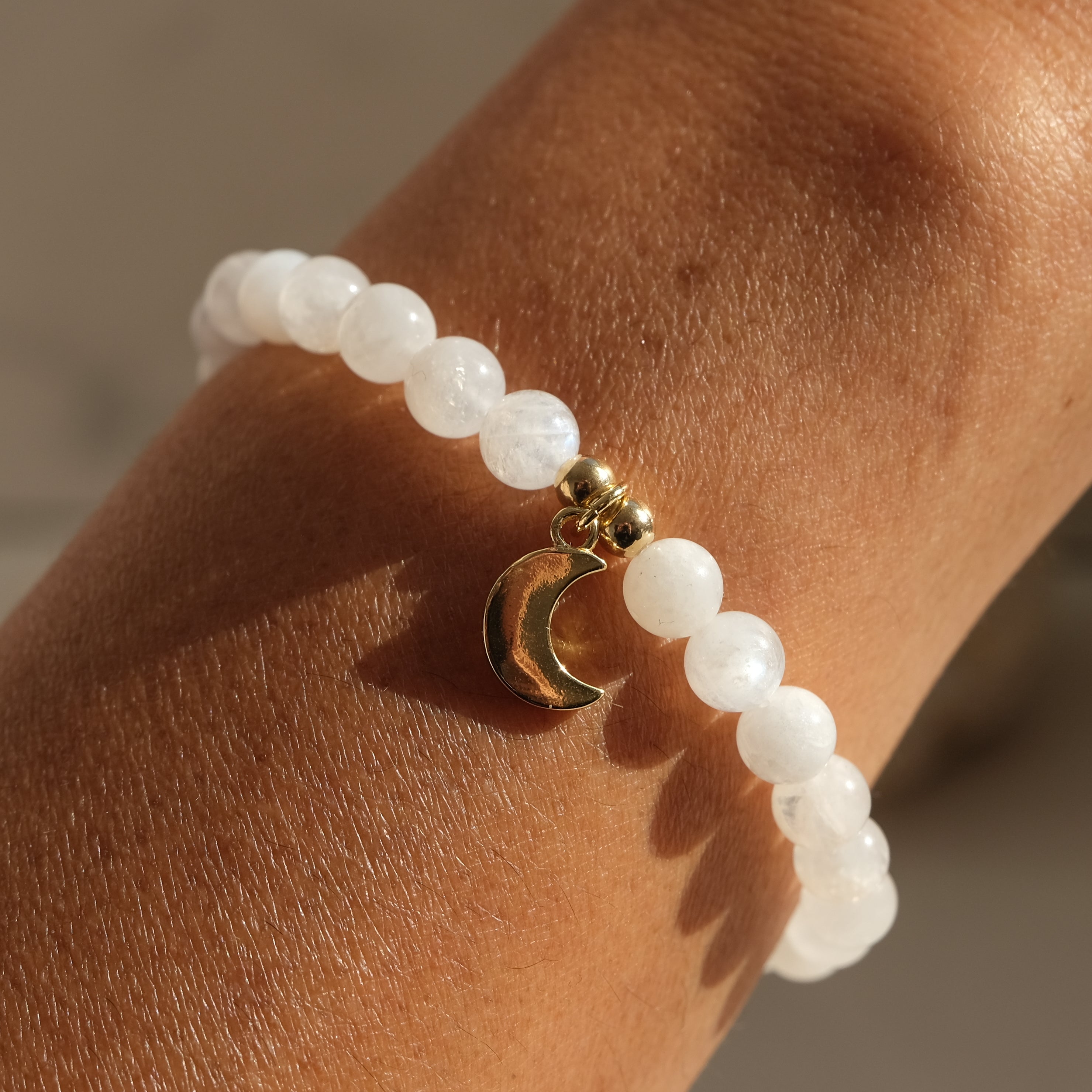 6mm moonstone gemstone bracelet with gold moon charm worn by a model