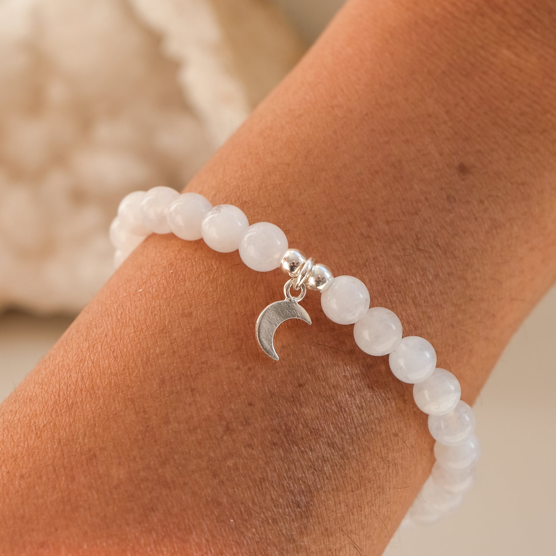 6mm moonstone gemstone bracelet with silver moon charm worn by a model