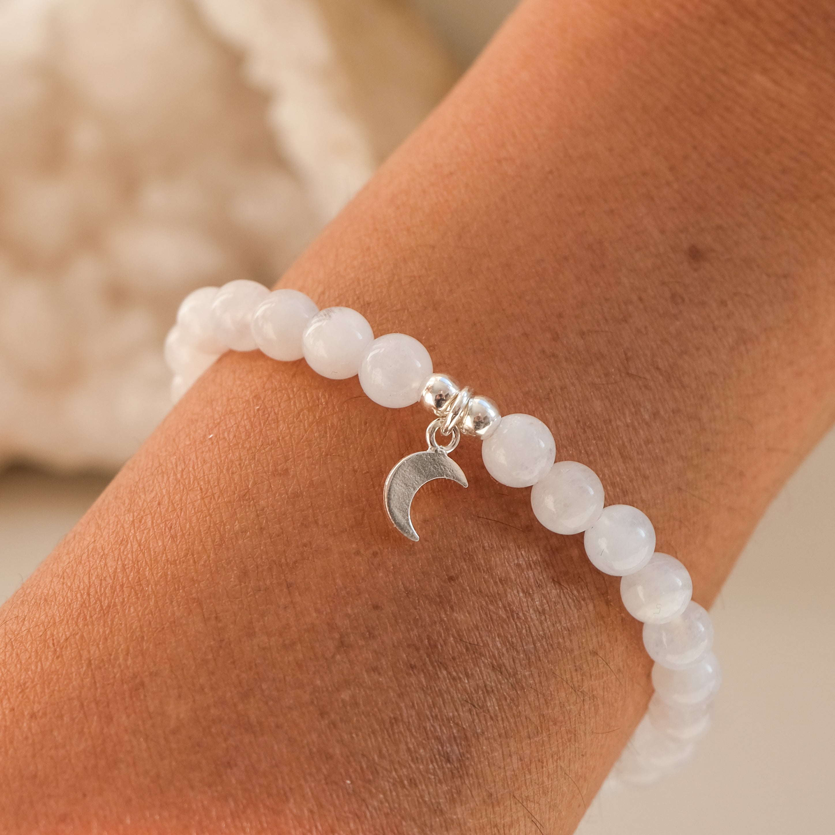 6mm moonstone gemstone bracelet with silver moon charm worn by a model