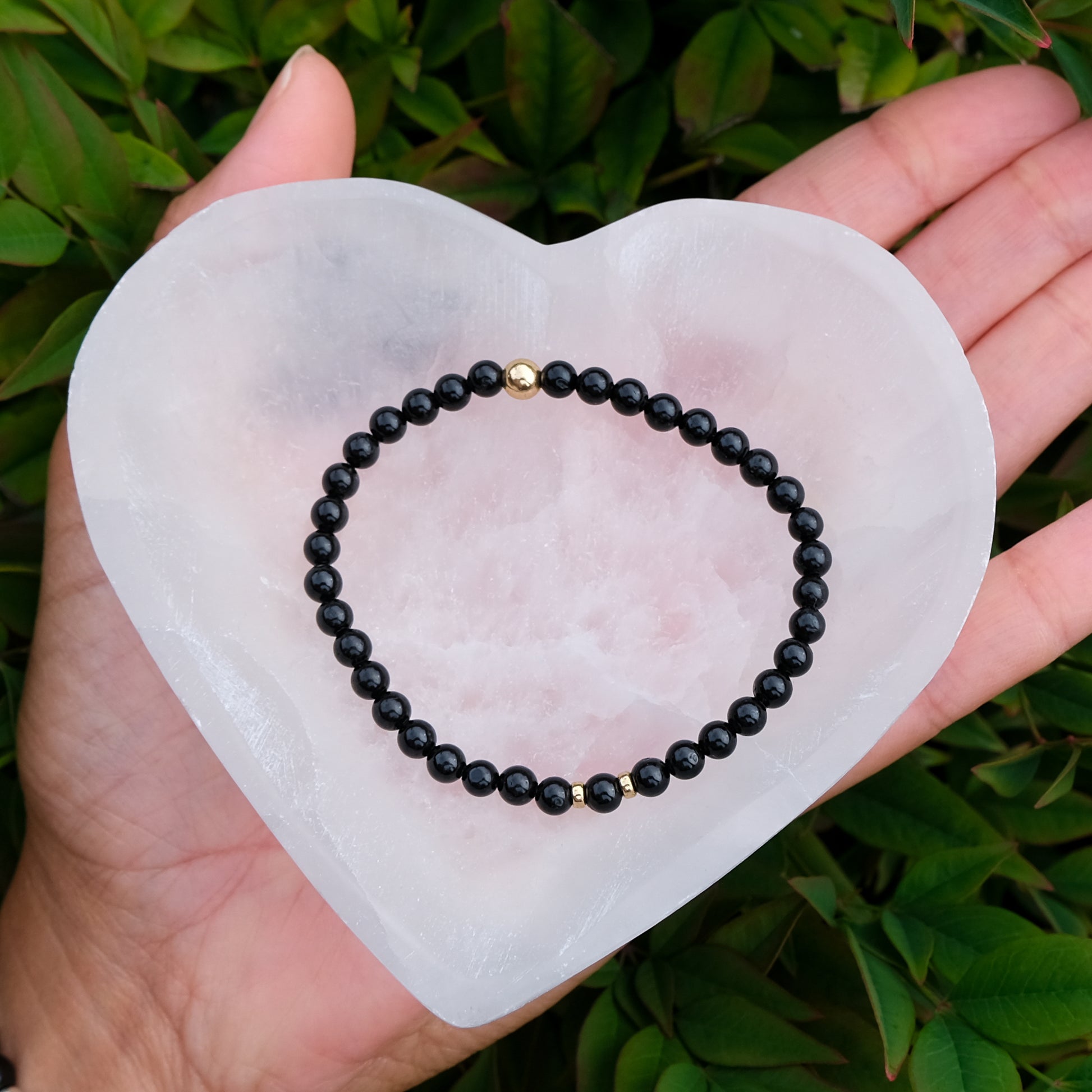 Selenite heart crystal charging bowl with a gemstone bracelet inside