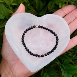 Selenite heart crystal charging bowl with a gemstone bracelet inside