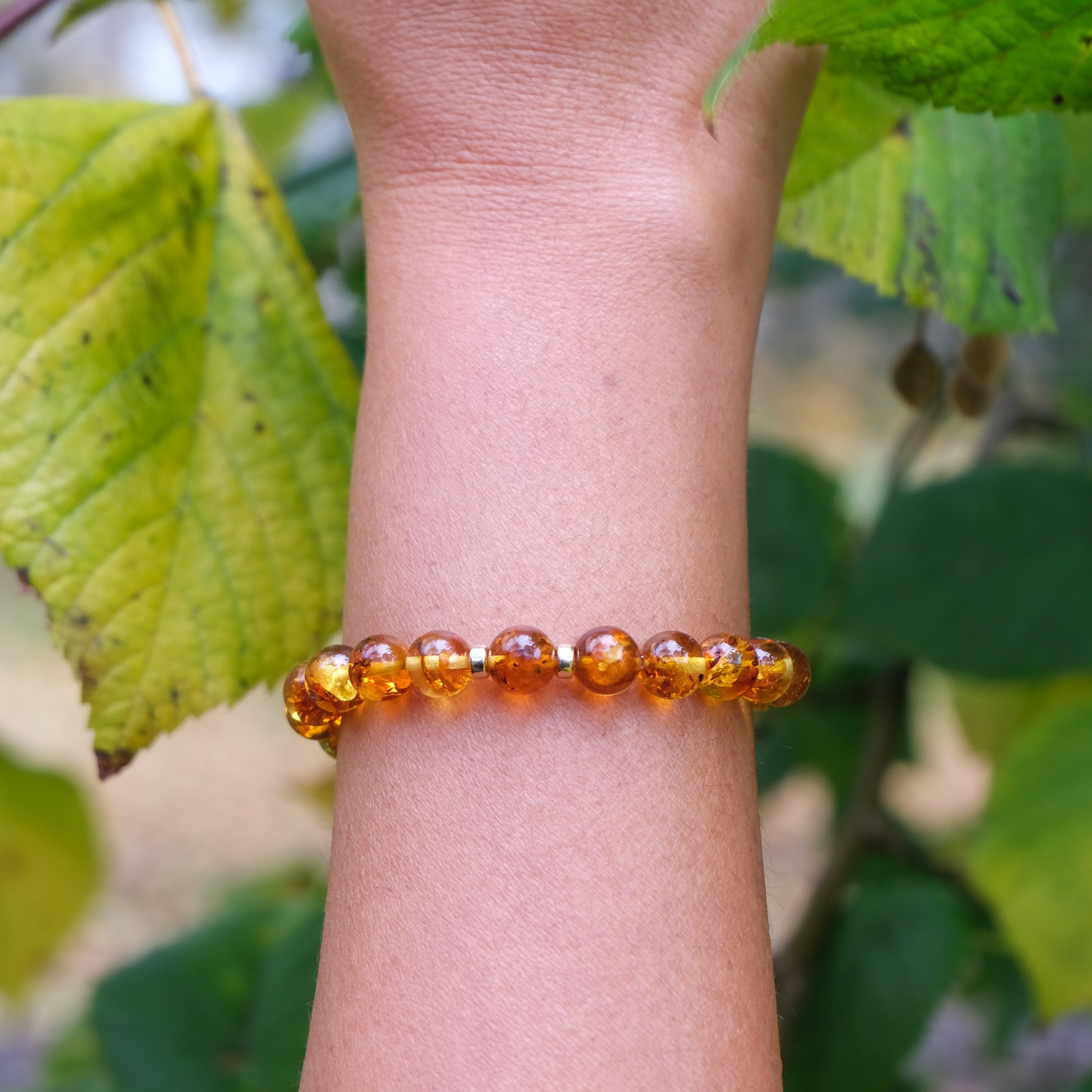 Amber beaded bracelet with gold accessories worn on a model's wrist