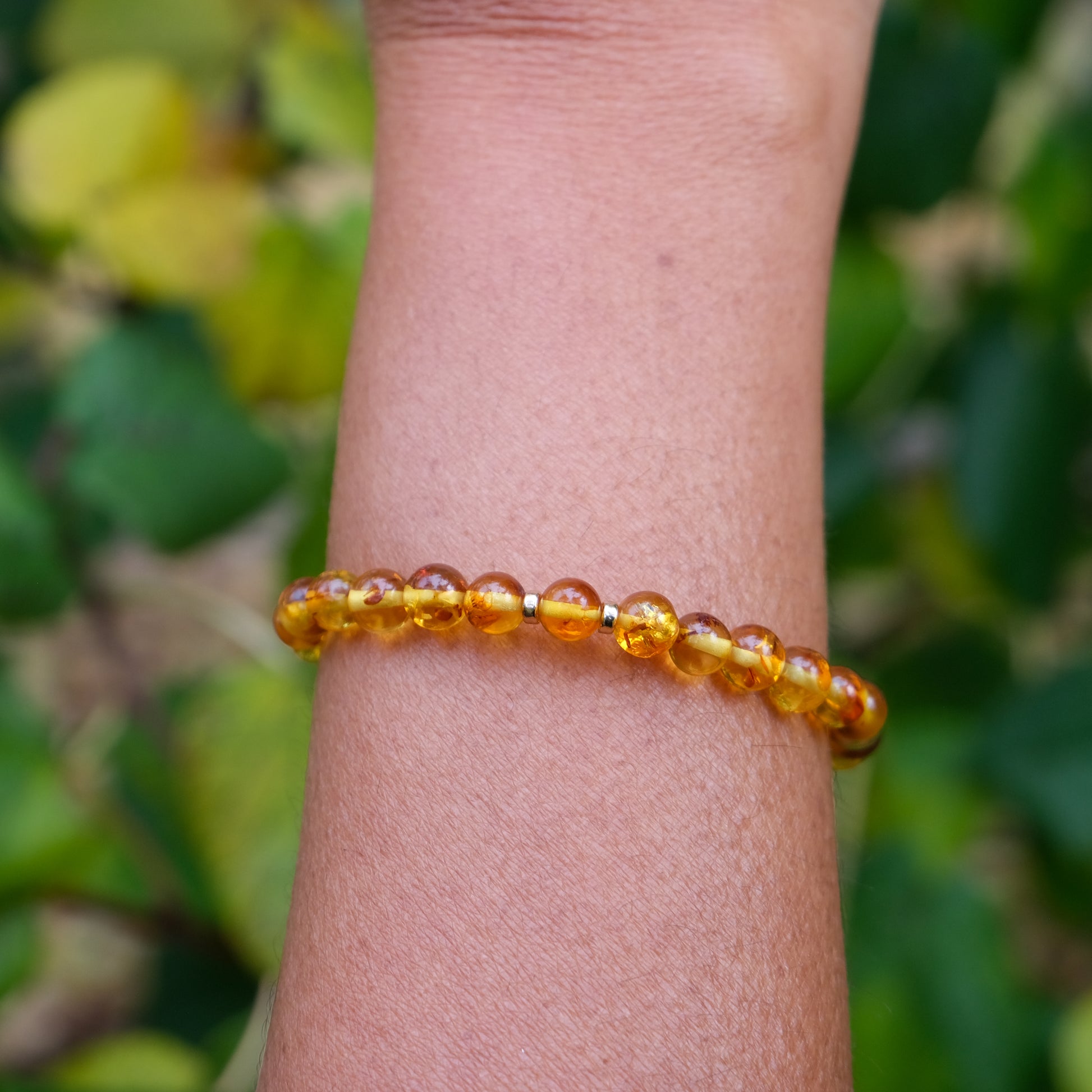 6mm Amber beaded bracelet with gold accessories worn on a model's wrist