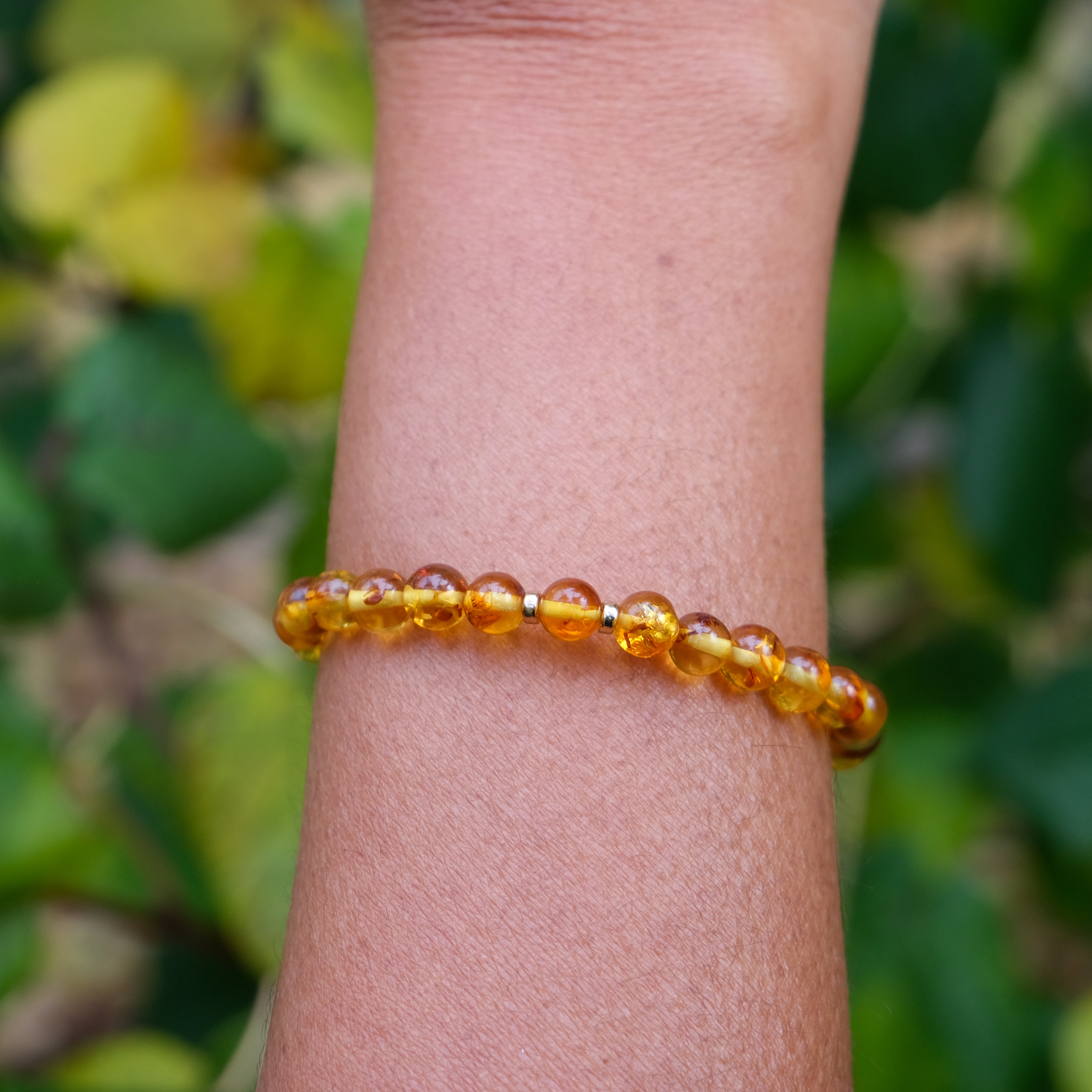 6mm Amber beaded bracelet with gold accessories worn on a model's wrist
