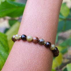 Garnet gemstone bracelet with gold accessories worn on a model's wrist