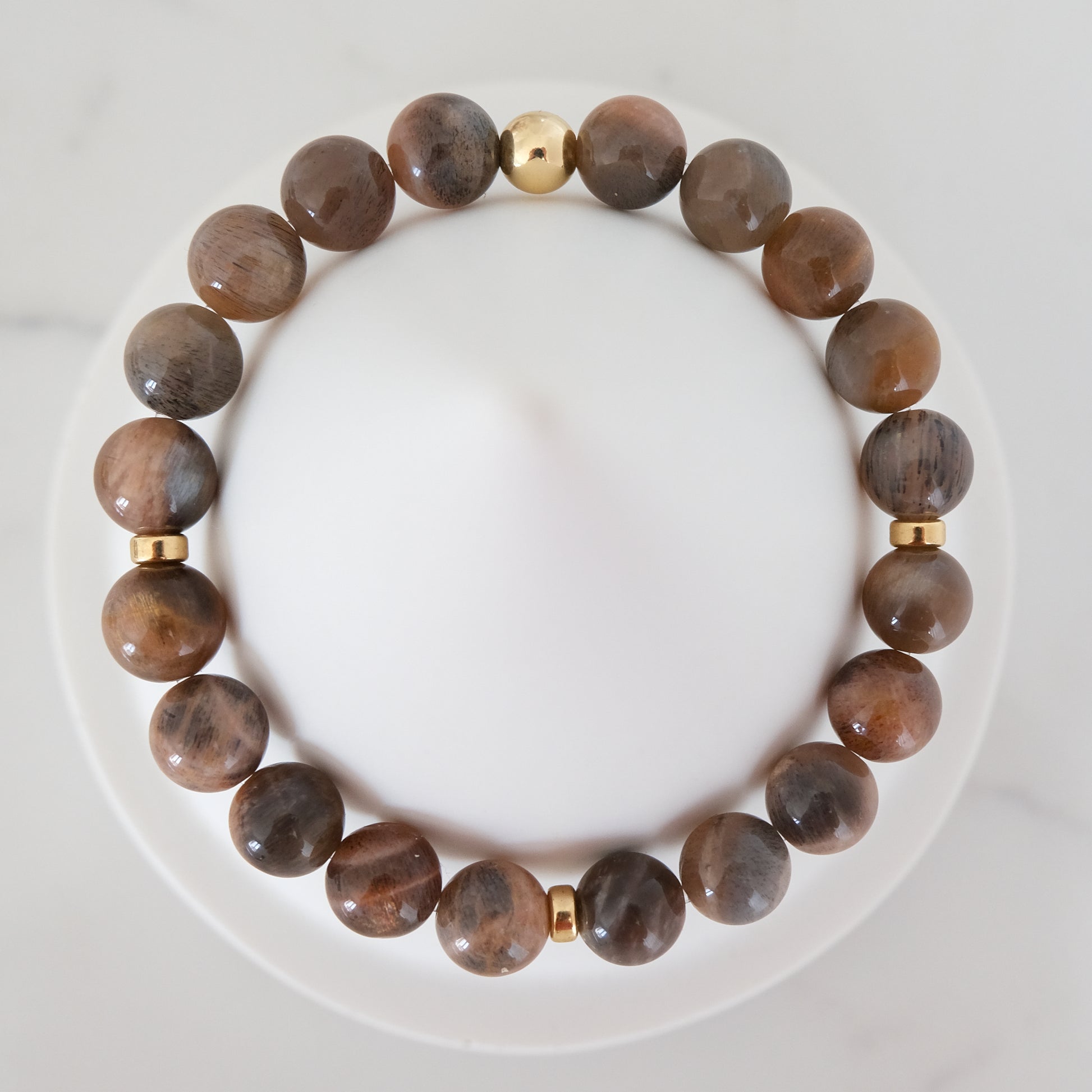 Black moonstone and sunstone gemstone bracelet with gold accessories from above