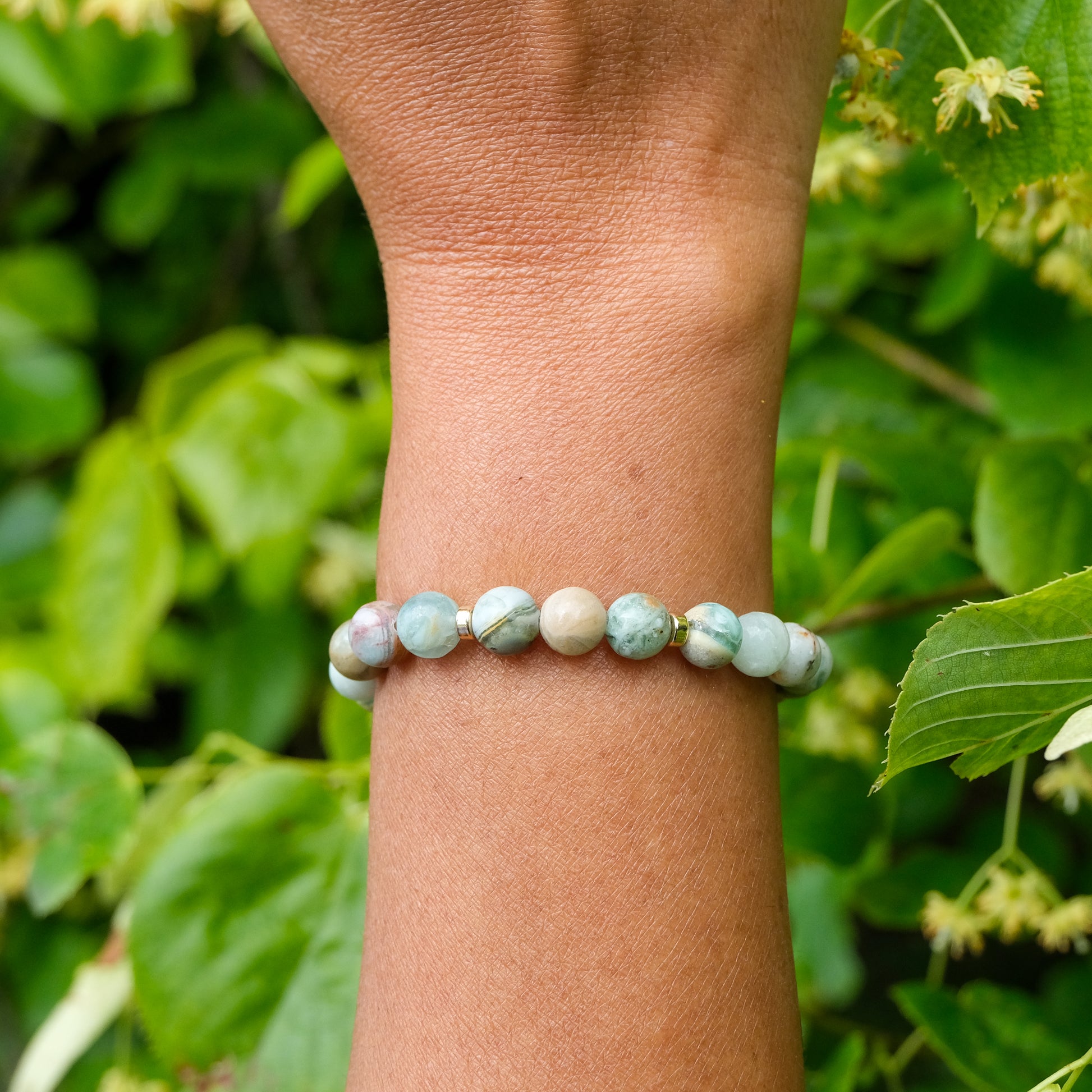 Green quartz gemstone bracelet with gold accessories worn on a model's wrist