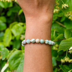 Green quartz gemstone bracelet with gold accessories worn on a model's wrist