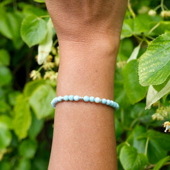 4mm larimar gemstone bracelet with gold accessories on a model's wrist
