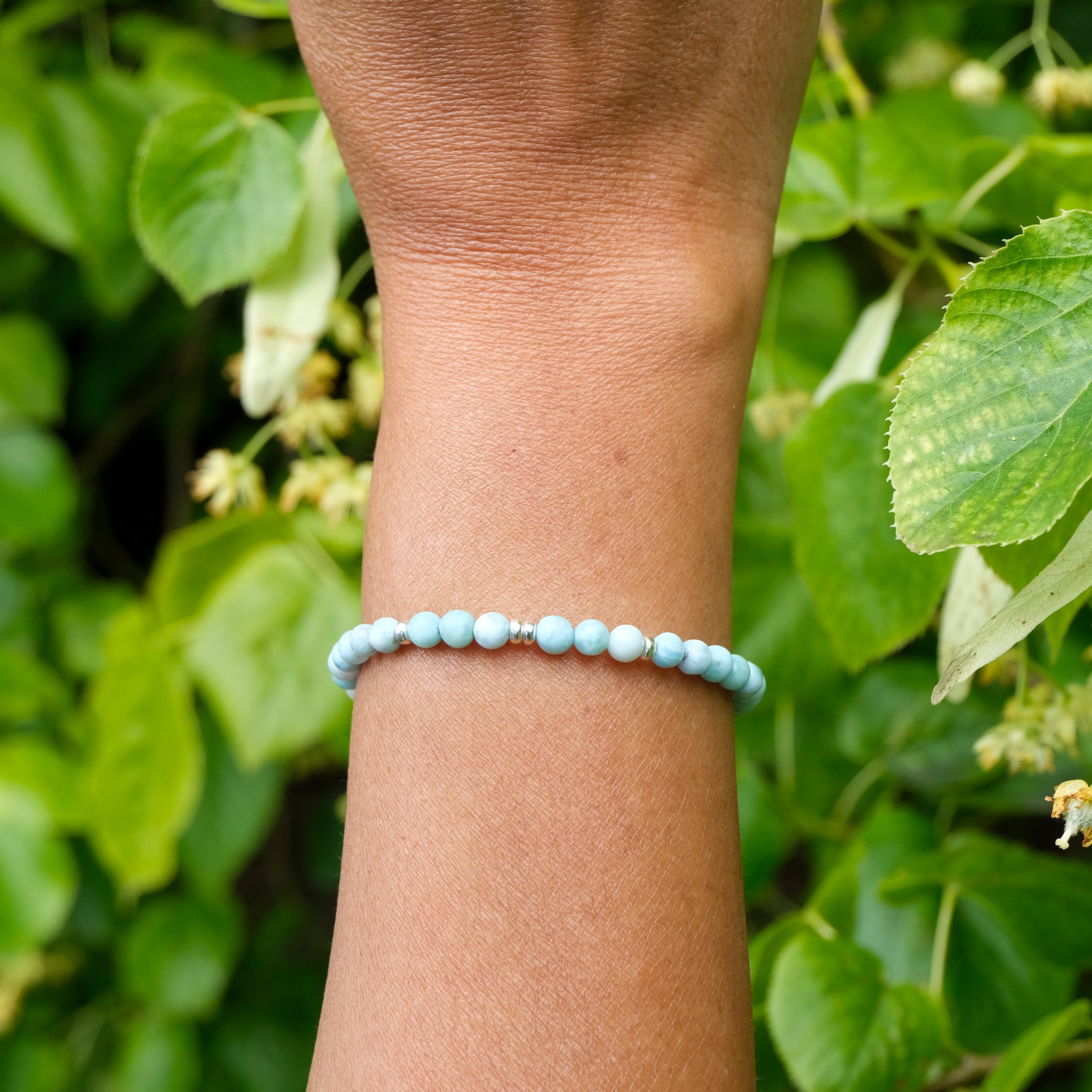 4mm larimar gemstone bracelet with gold accessories on a model's wrist