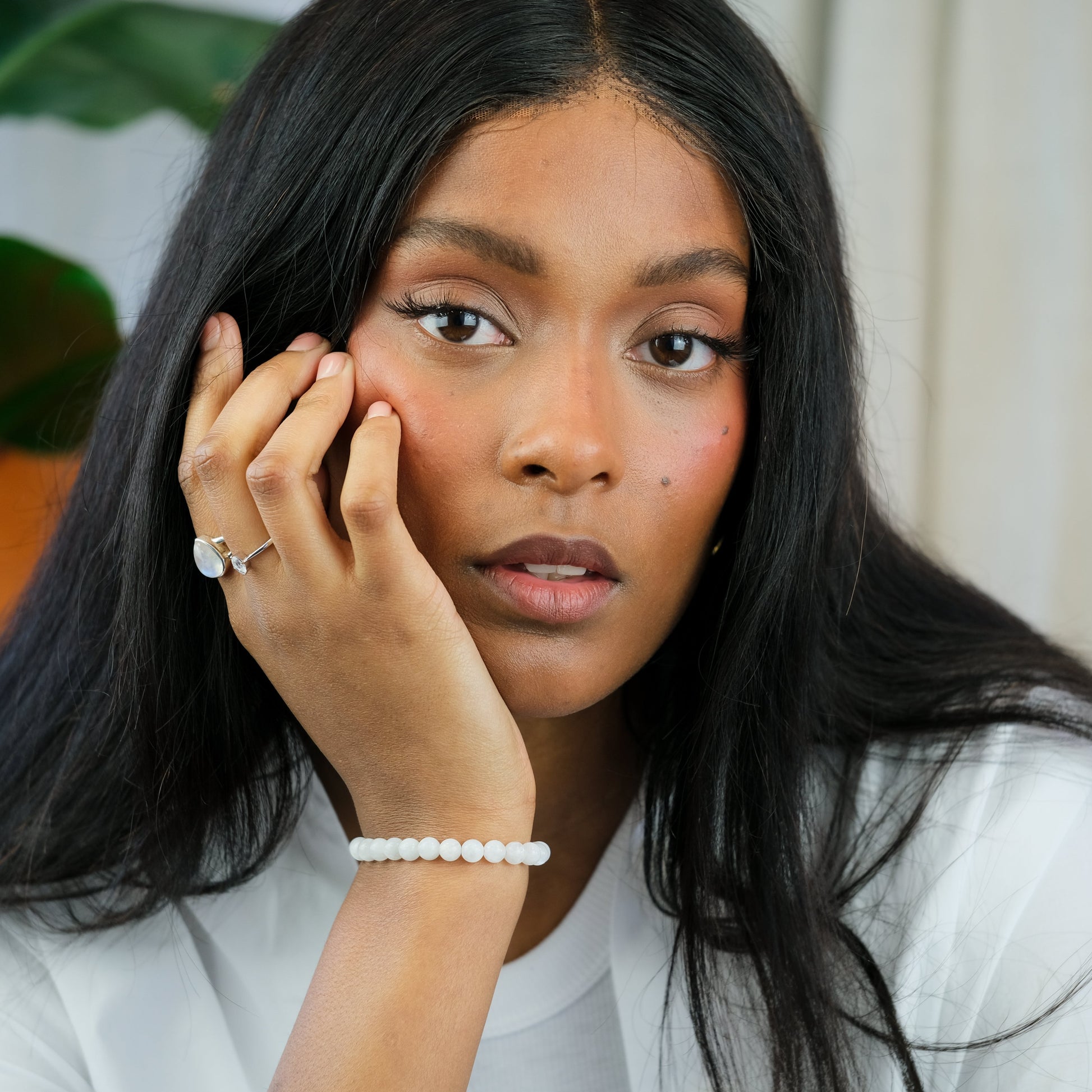 A model wearing a 6mm moonstone gemstone bracelet with moonstone rings in 925 sterling silver