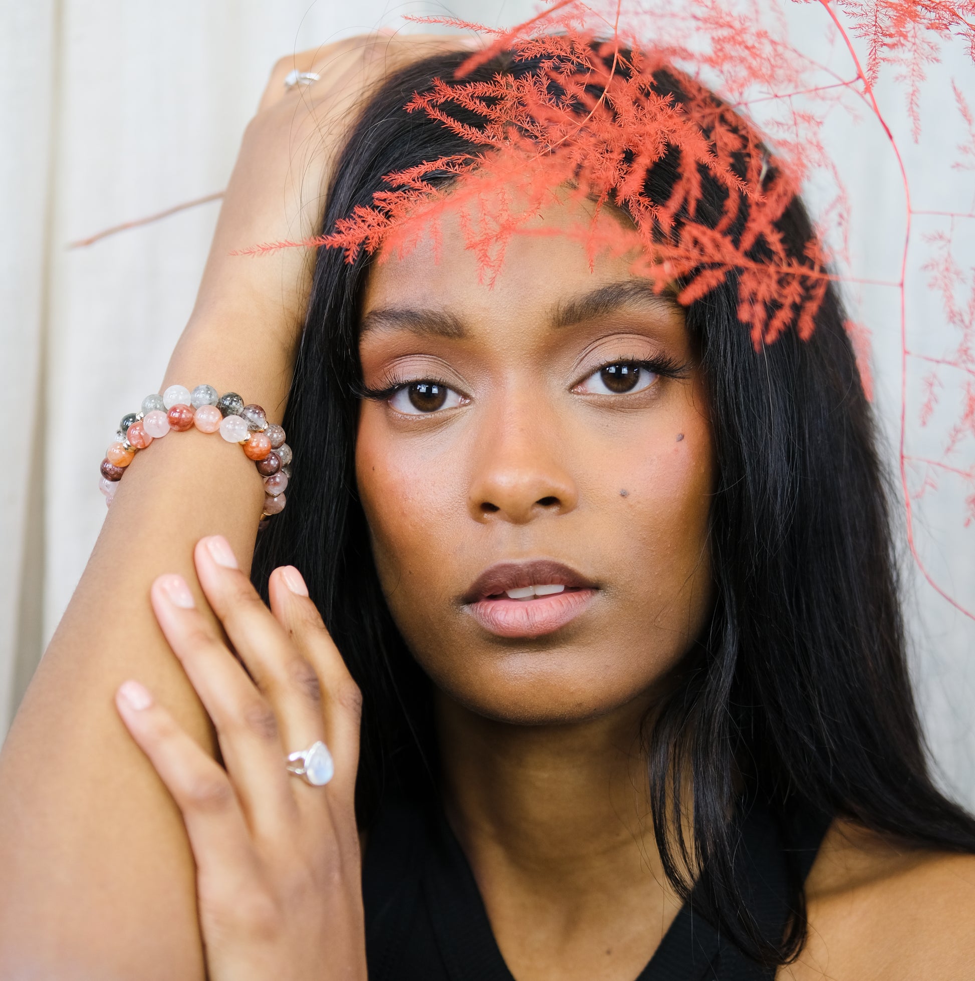 A model wearing a red phantom quartz gemstone bracelet with a green phantom quartz gemstone bracelet