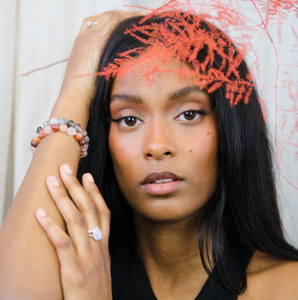 A model wearing a red phantom quartz gemstone bracelet with a green phantom quartz gemstone bracelet