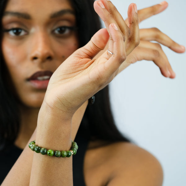 A model wearing a jade gemstone bracelet with gold accessories
