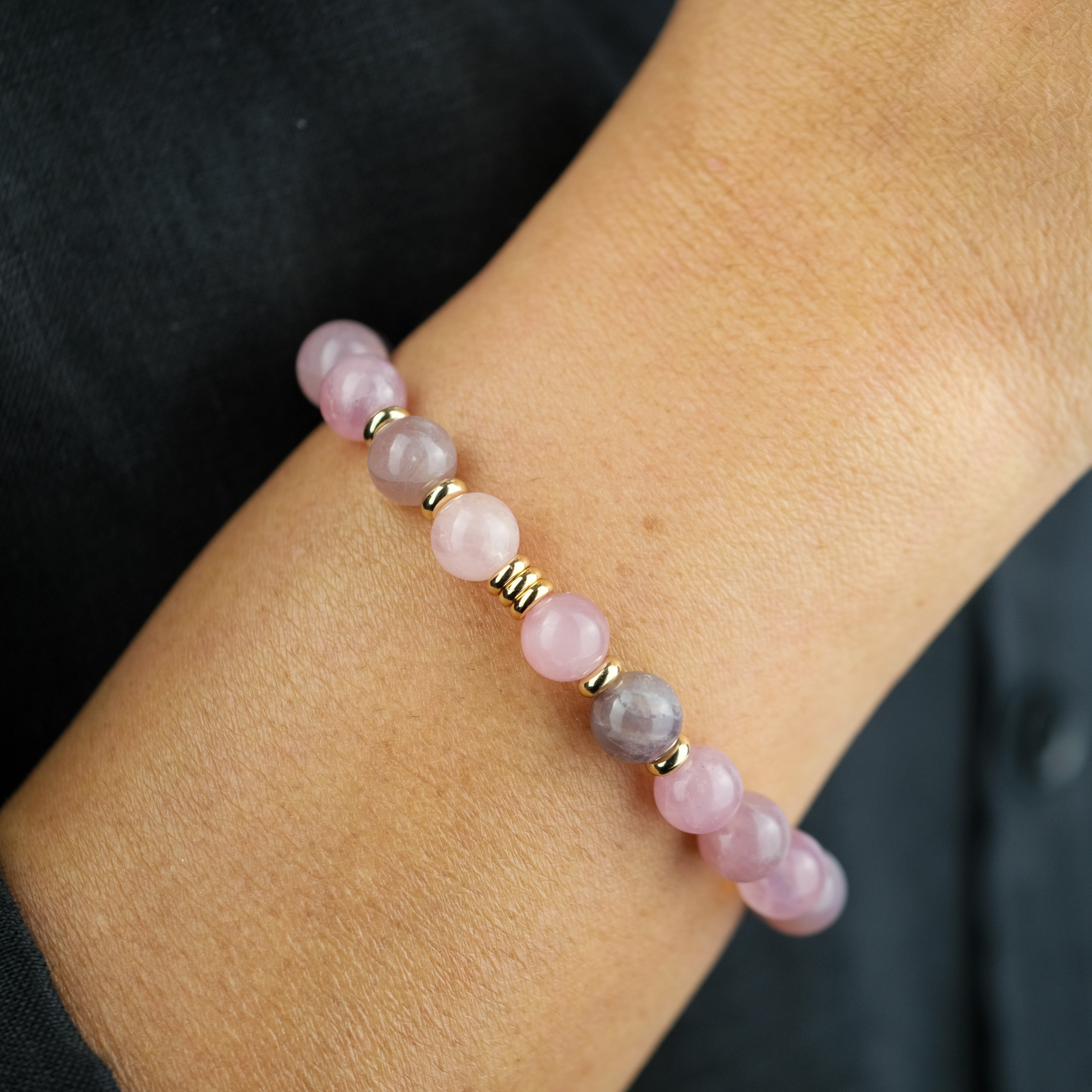 A model wearing a lavender rose quartz 8mm gemstone bracelet with gold accessories