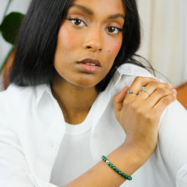 A model wearing a 6mm malachite gemstone bracelet with green onyx rings