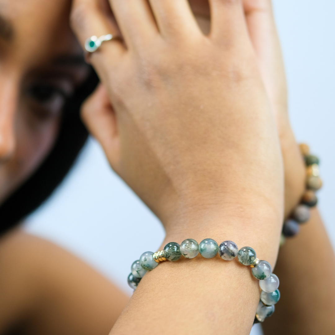 A model wearing a moss agate gemstone bracelet with gold accessories