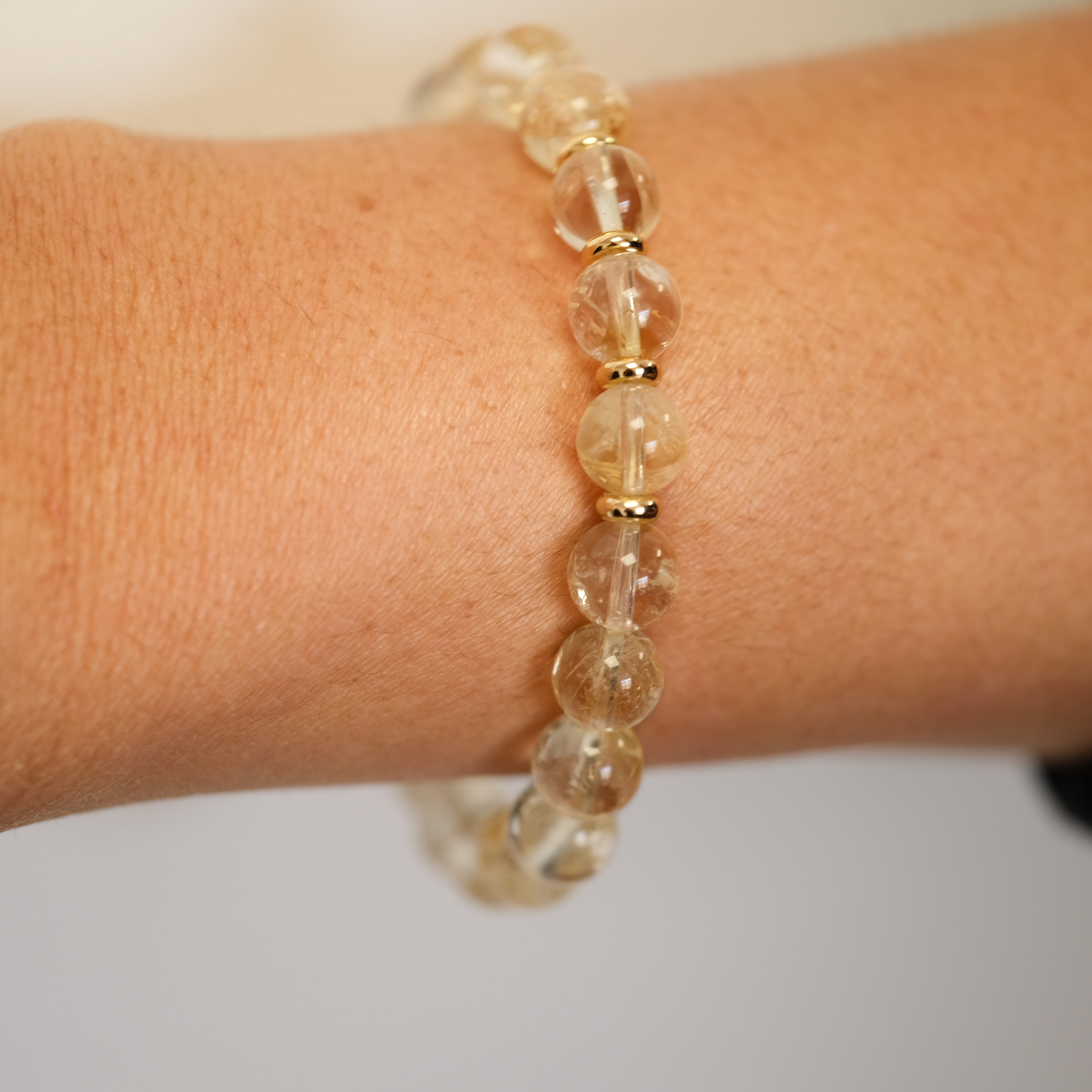 Citrine gemstone bracelet with gold accessories worn on a model's wrist