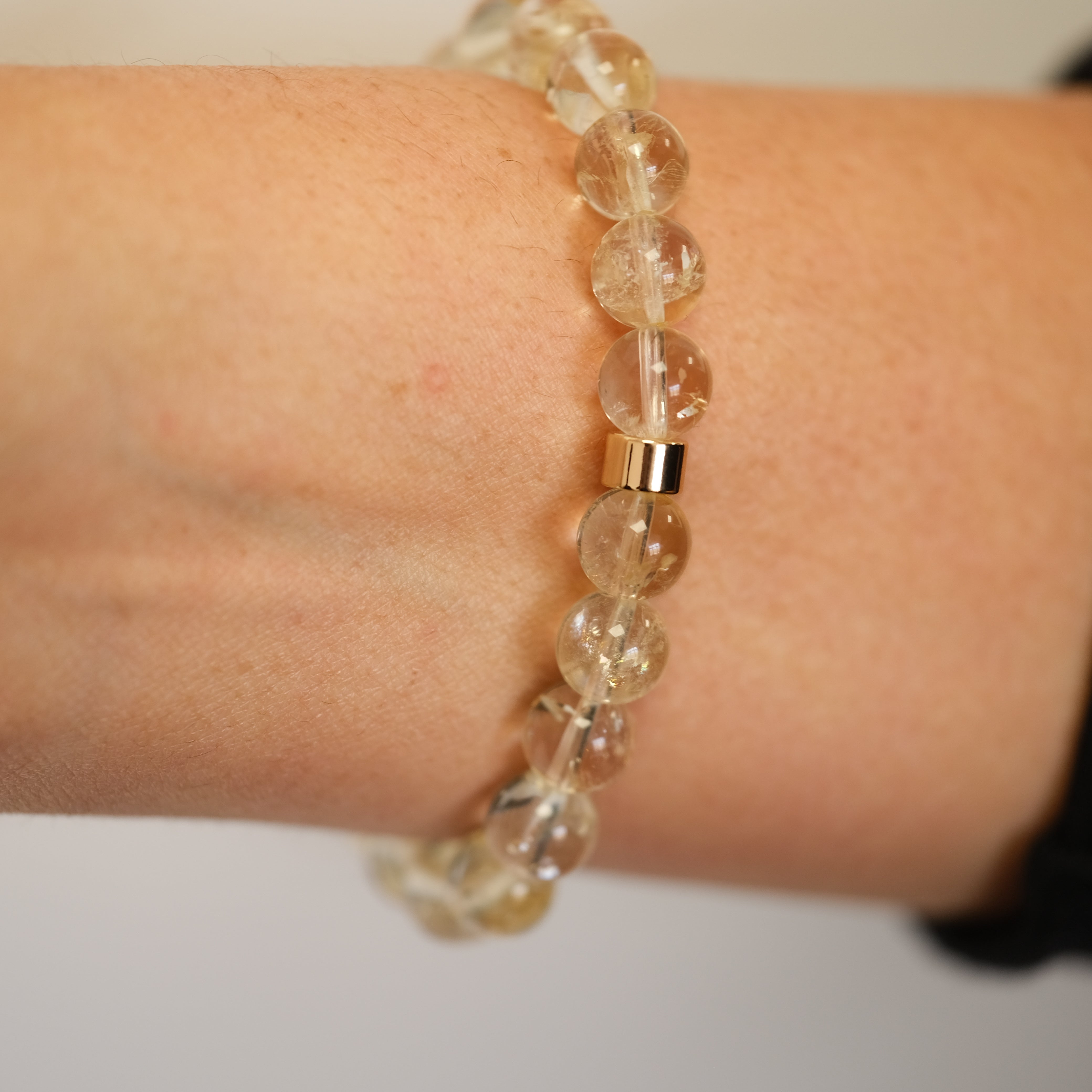Citrine gemstone bracelet with gold accessories worn on a model's wrist from the back