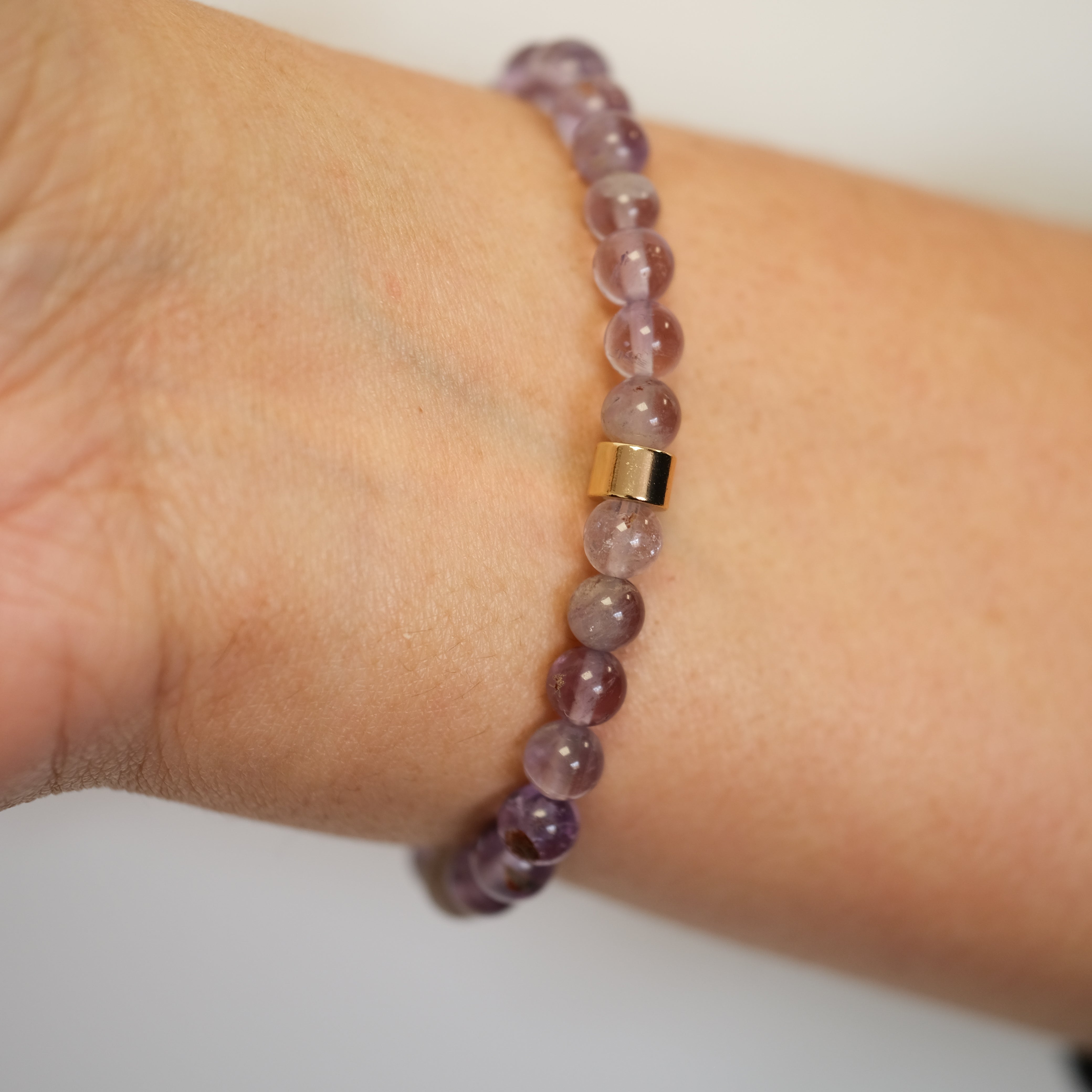 A phantom amethyst gemstone bracelet in 6mm beads worn on a model's wrist from behind