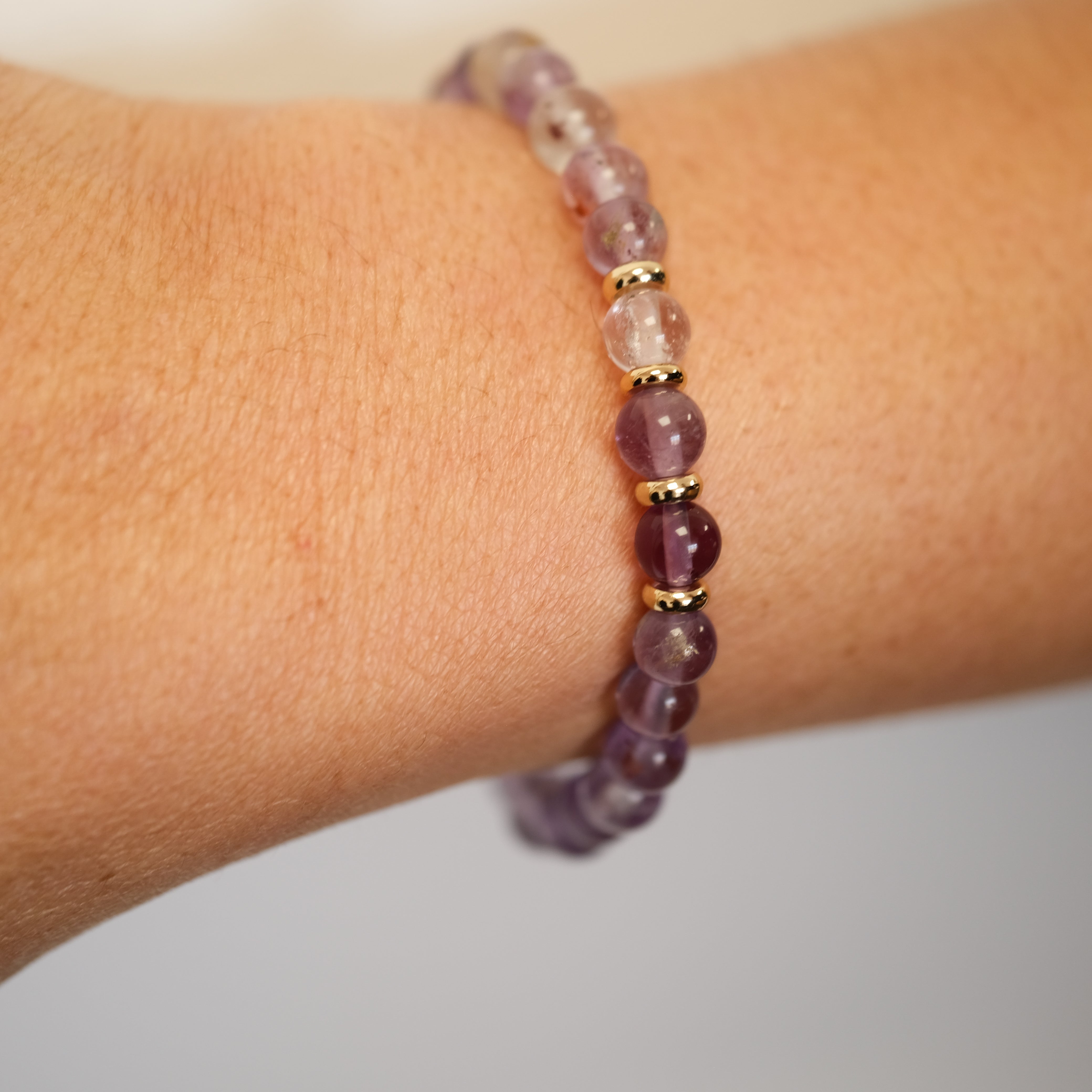 A phantom amethyst gemstone bracelet in 6mm beads worn on a model's wrist