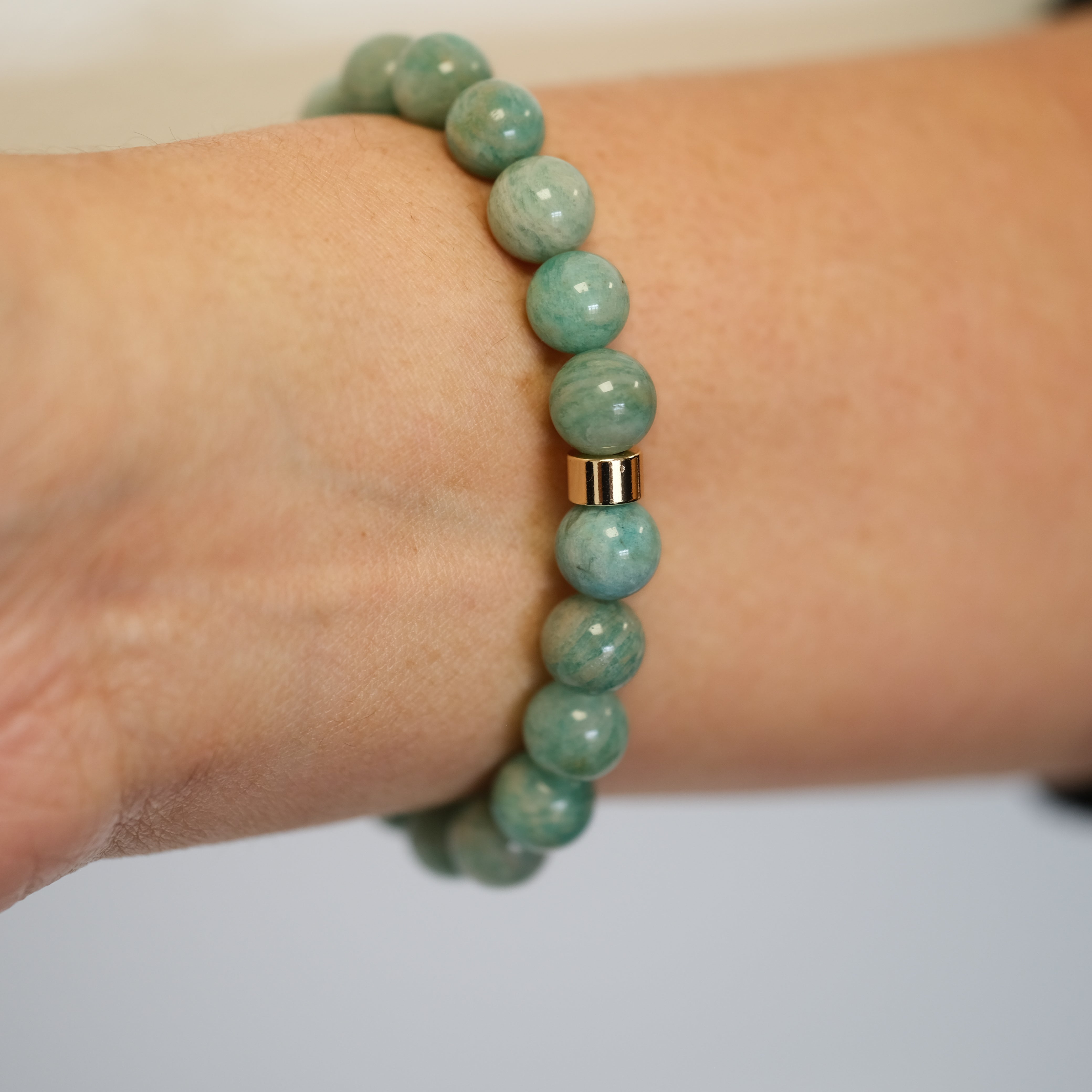 Amazonite gemstone bracelet with gold accessories worn on a model's wrist from the back