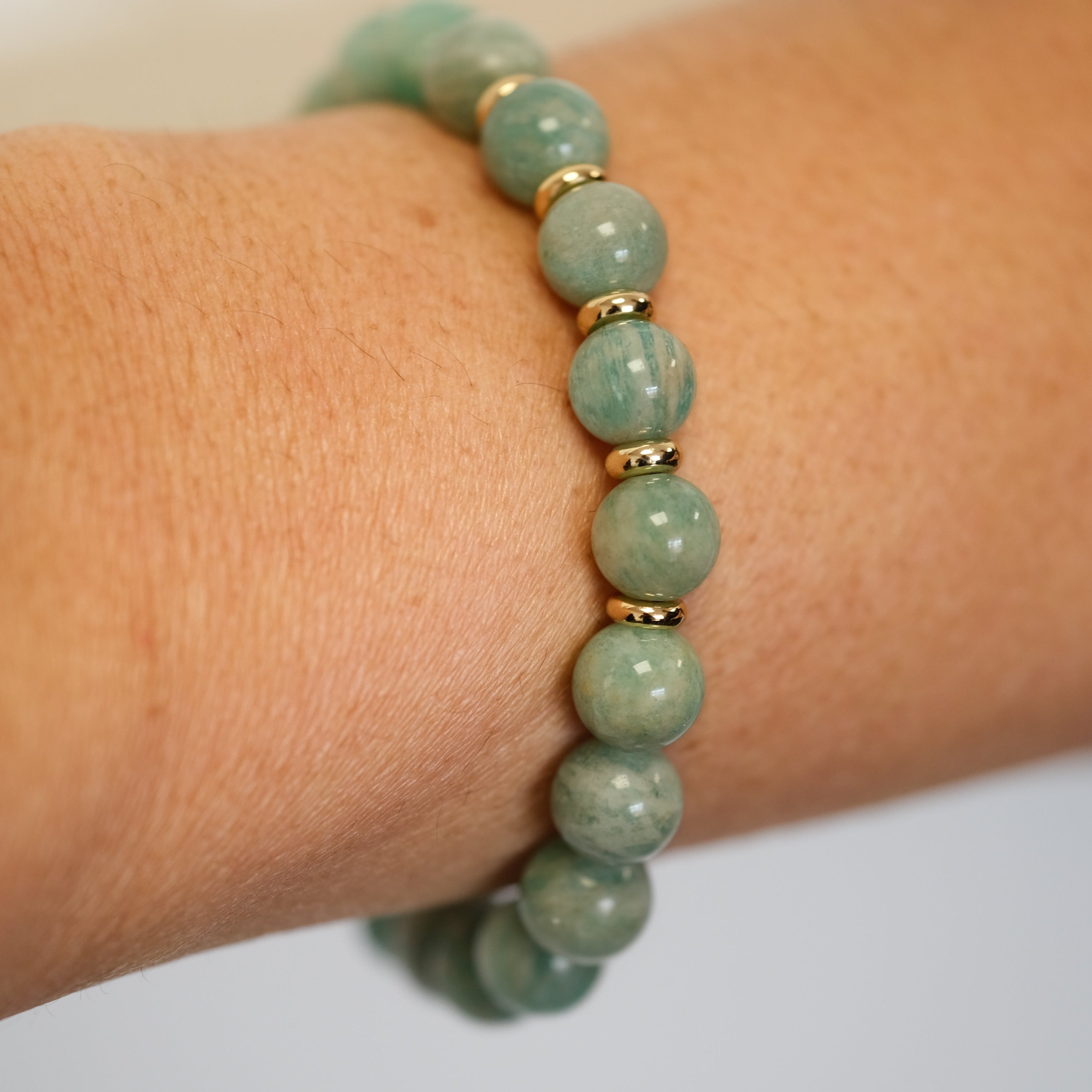 Amazonite gemstone bracelet with gold accessories worn on a model's wrist