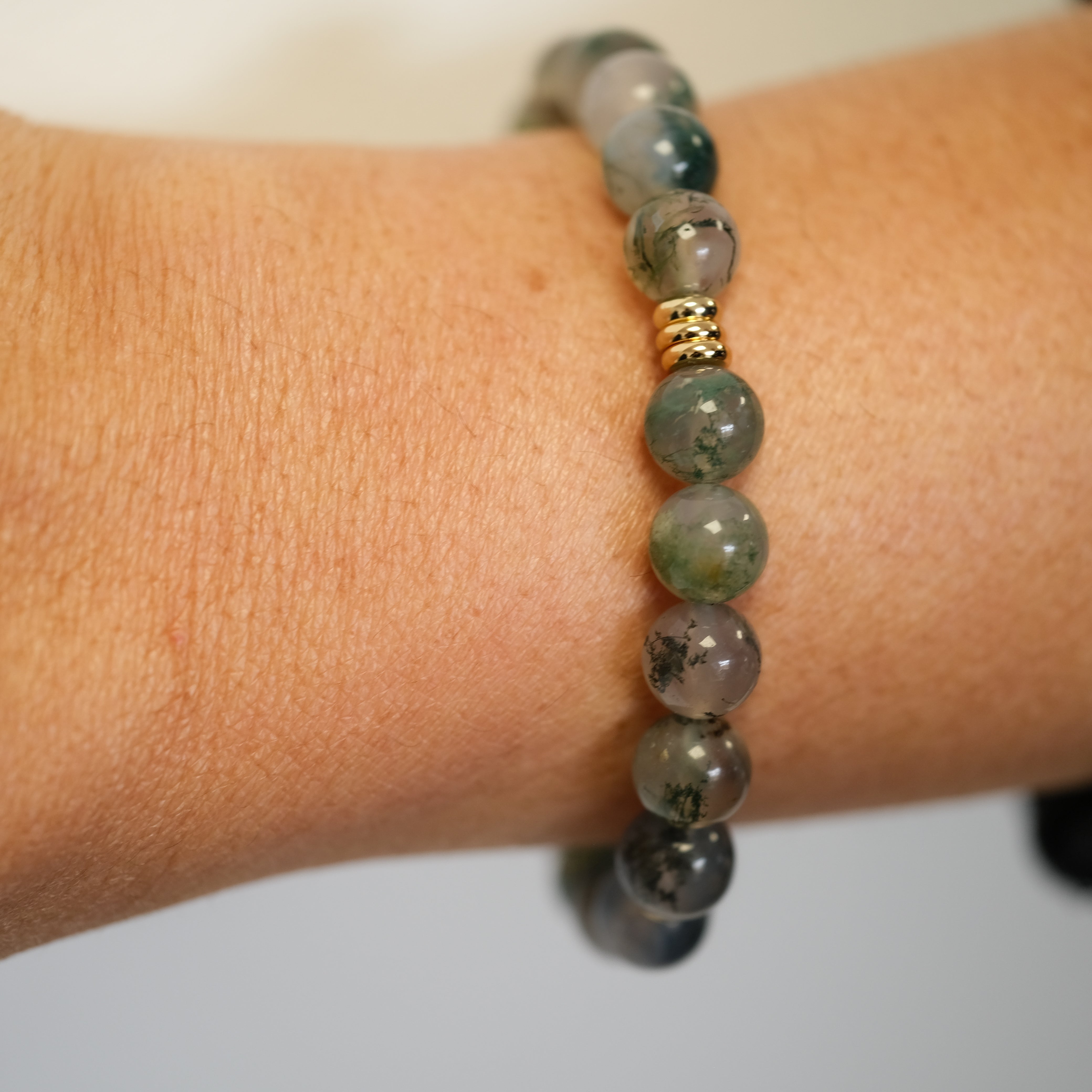 A moss agate gemstone bracelet worn on a model's wrist