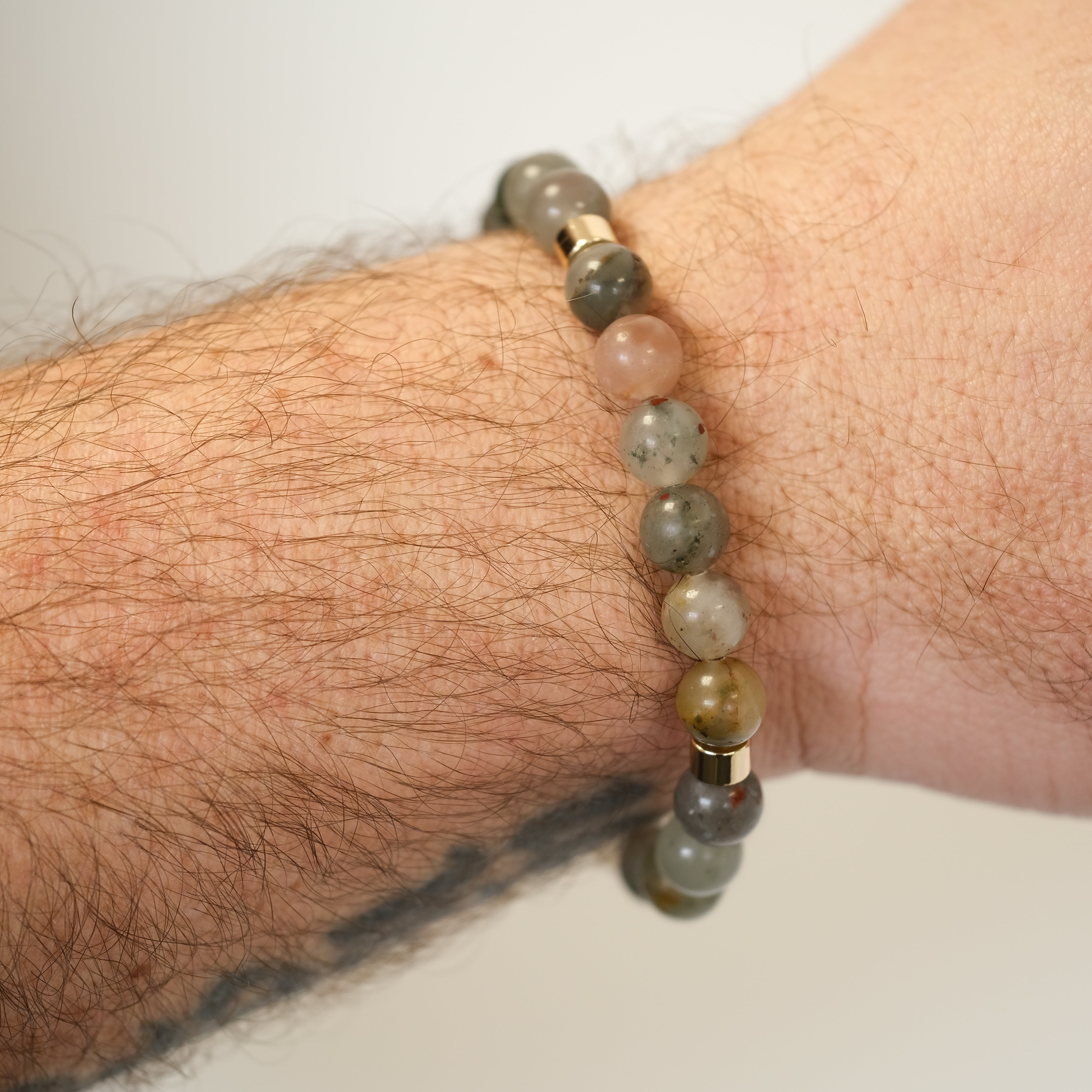 A bloodstone gemstone bracelet worn on a model's wrist