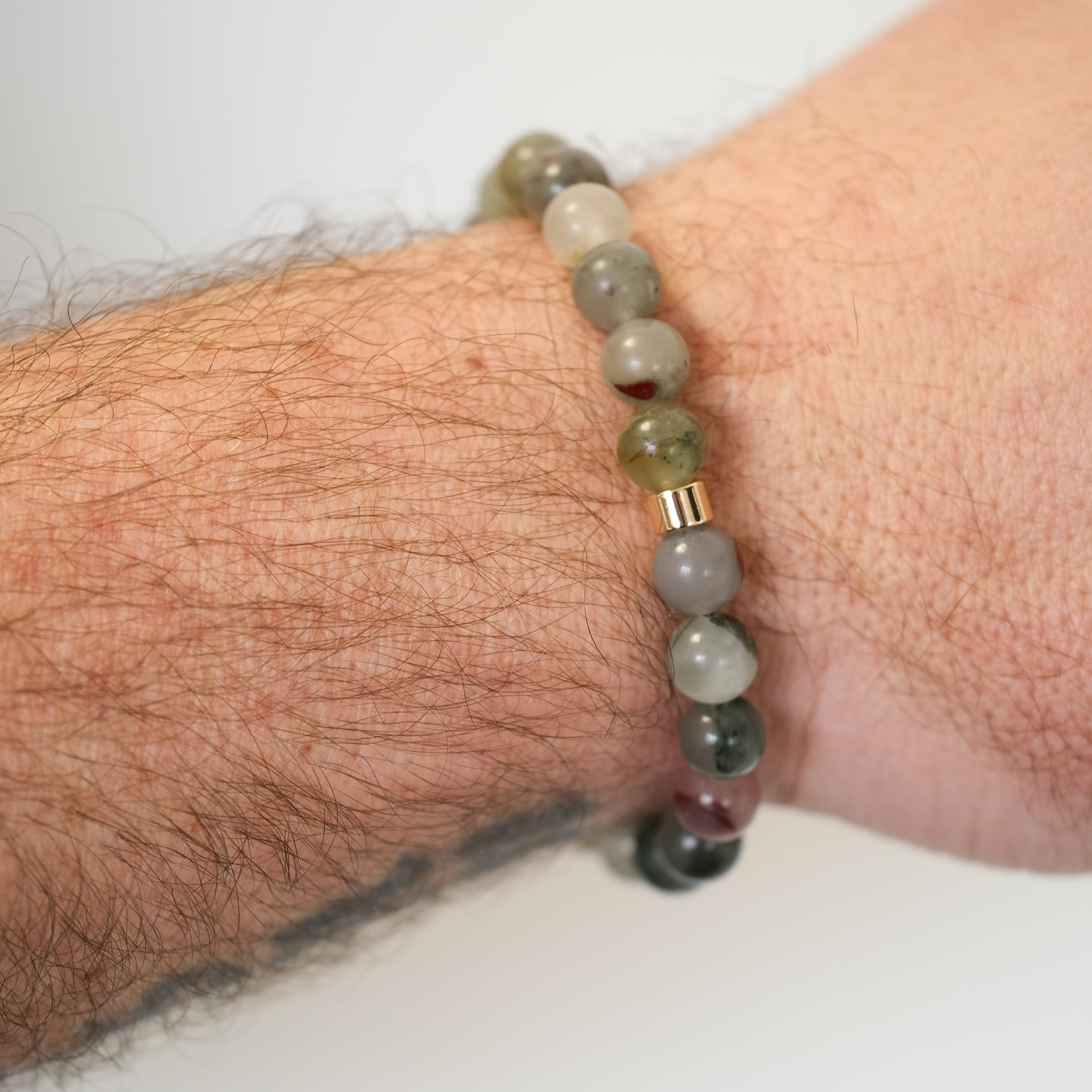 A bloodstone gemstone bracelet worn on a model's wrist