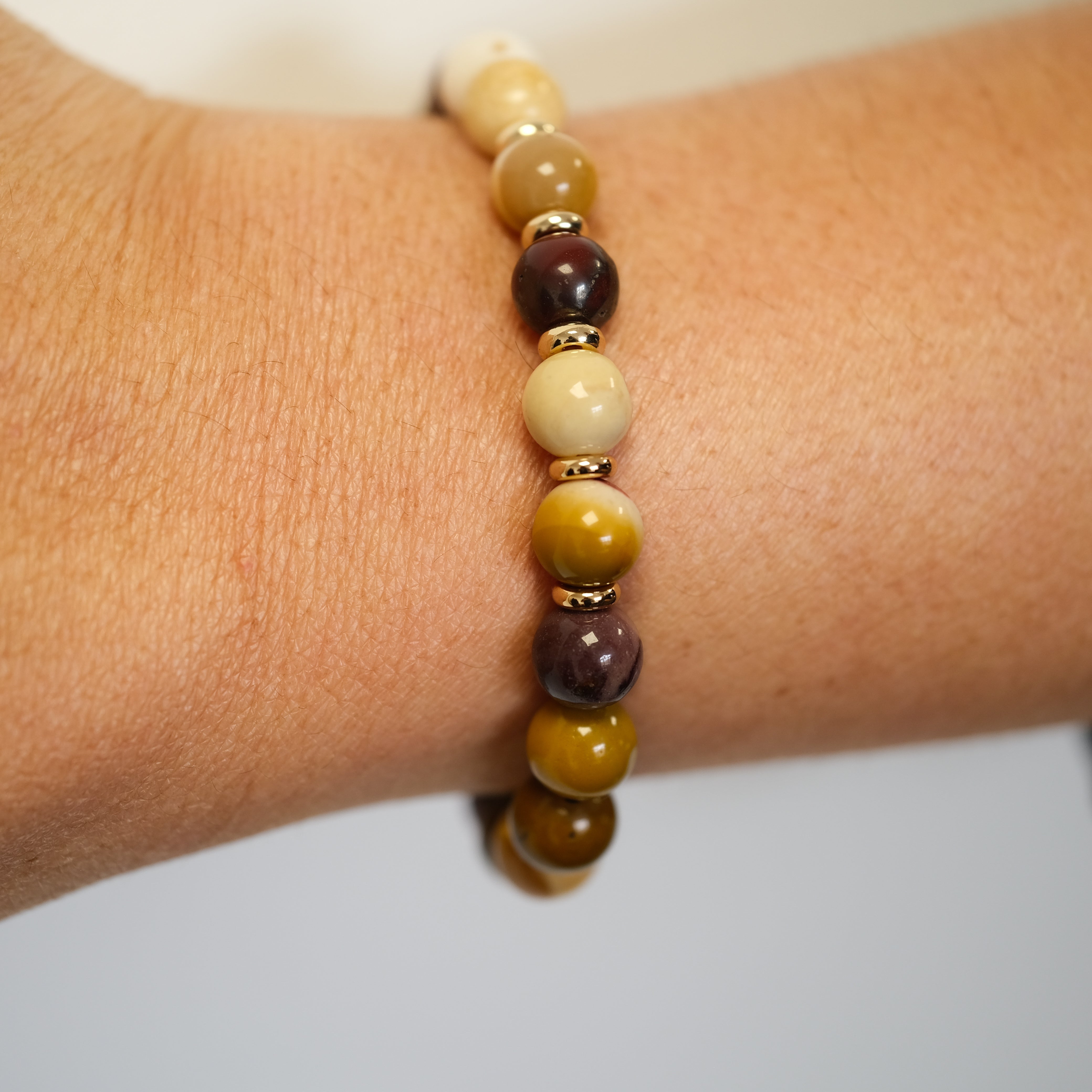 A mookaite gemstone bracelet worn on a model's wrist