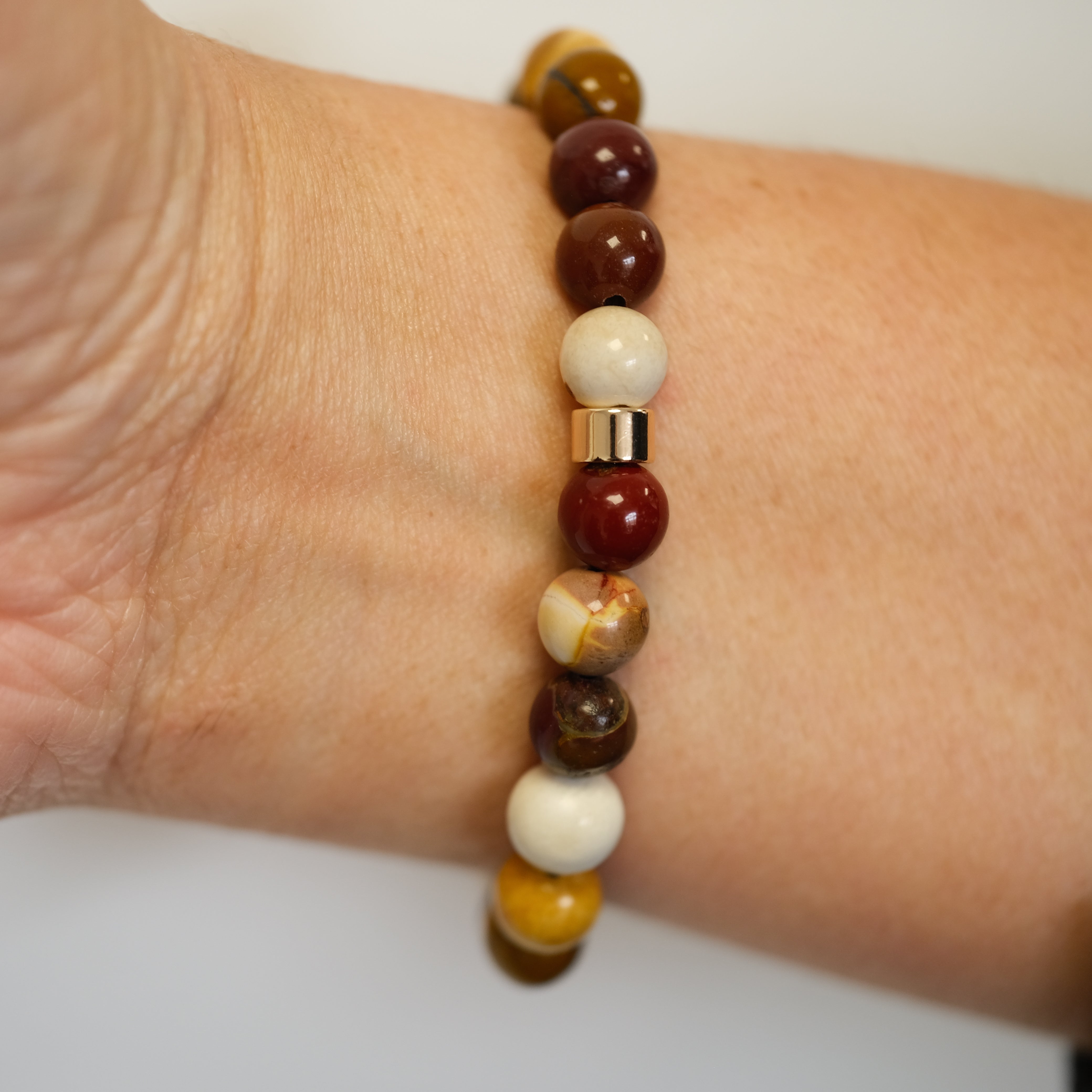 A mookaite gemstone bracelet worn on a model's wrist from behind