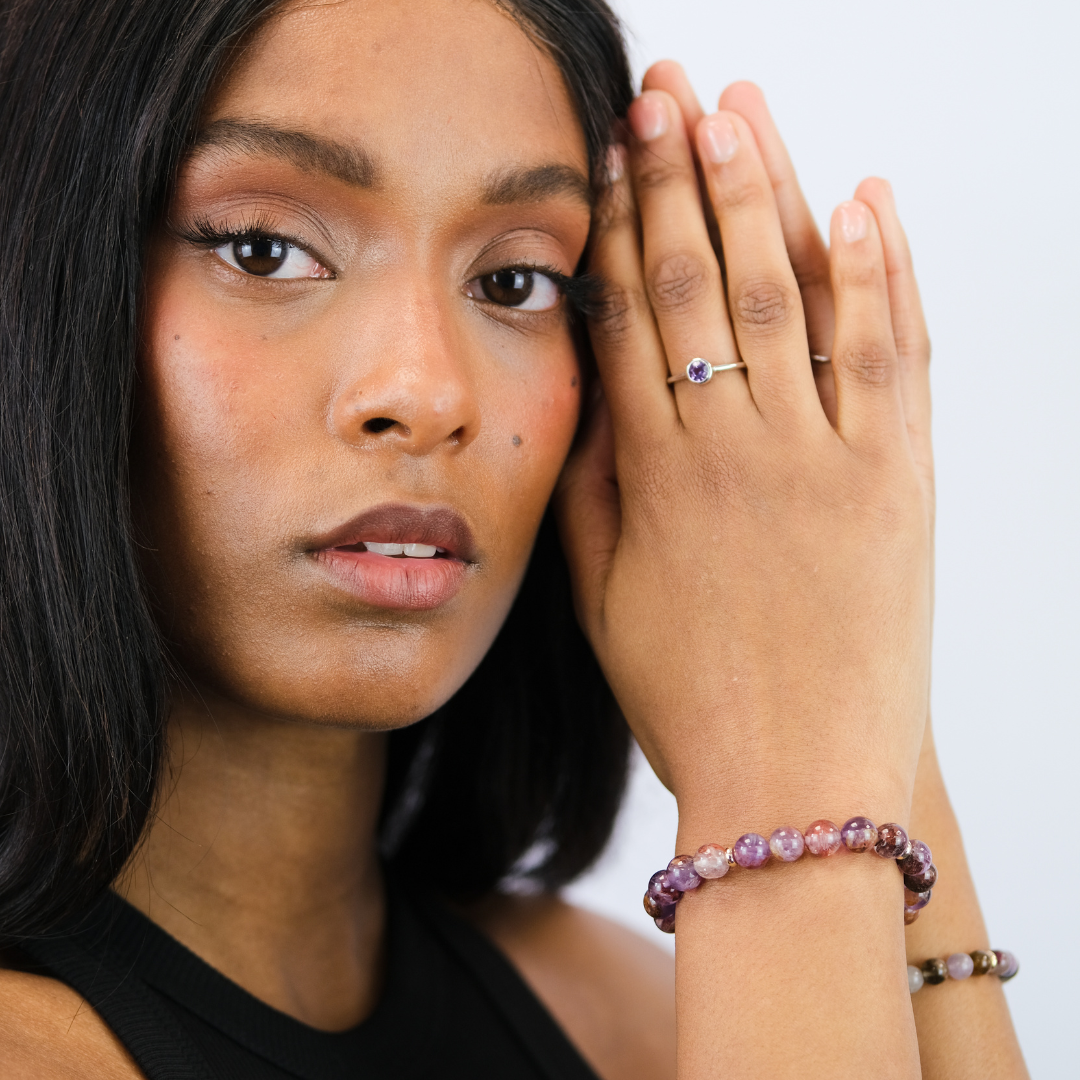 A model wearing a phantom amethyst gemstone bracelet with gold accessories