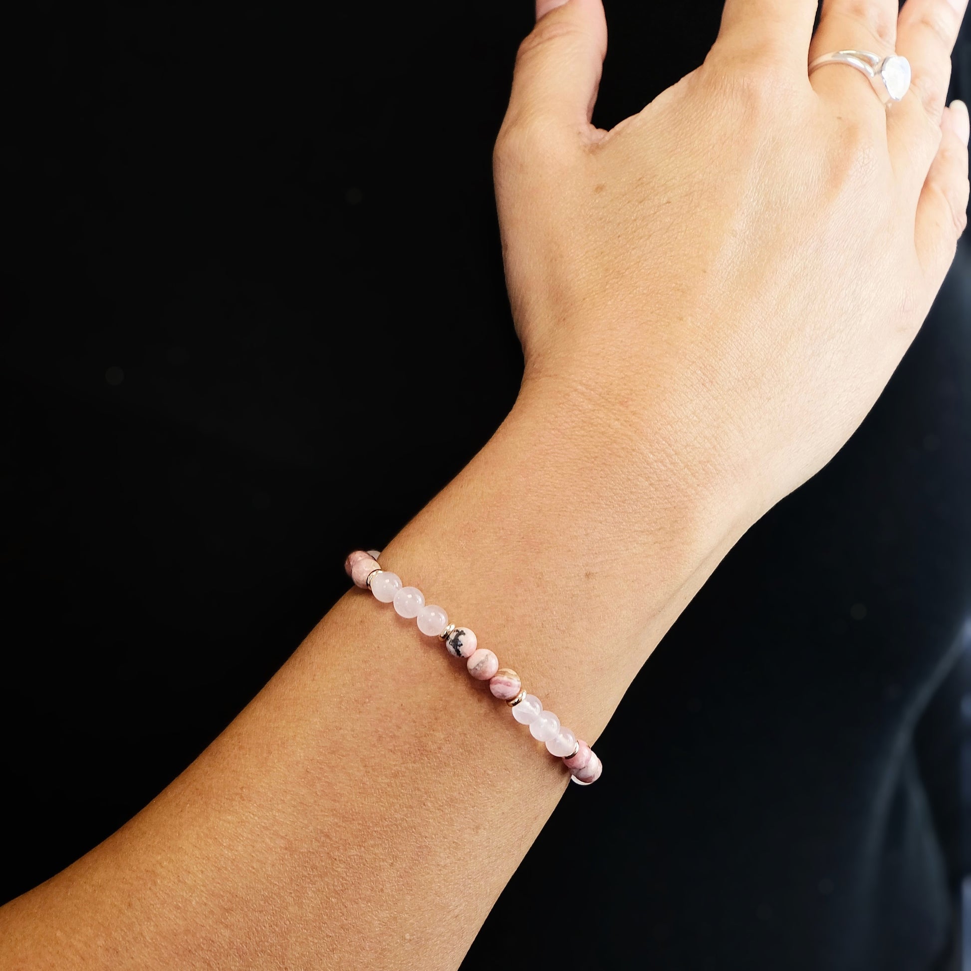 A model wearing a rhodochrosite and rose quartz gemstone bracelet
