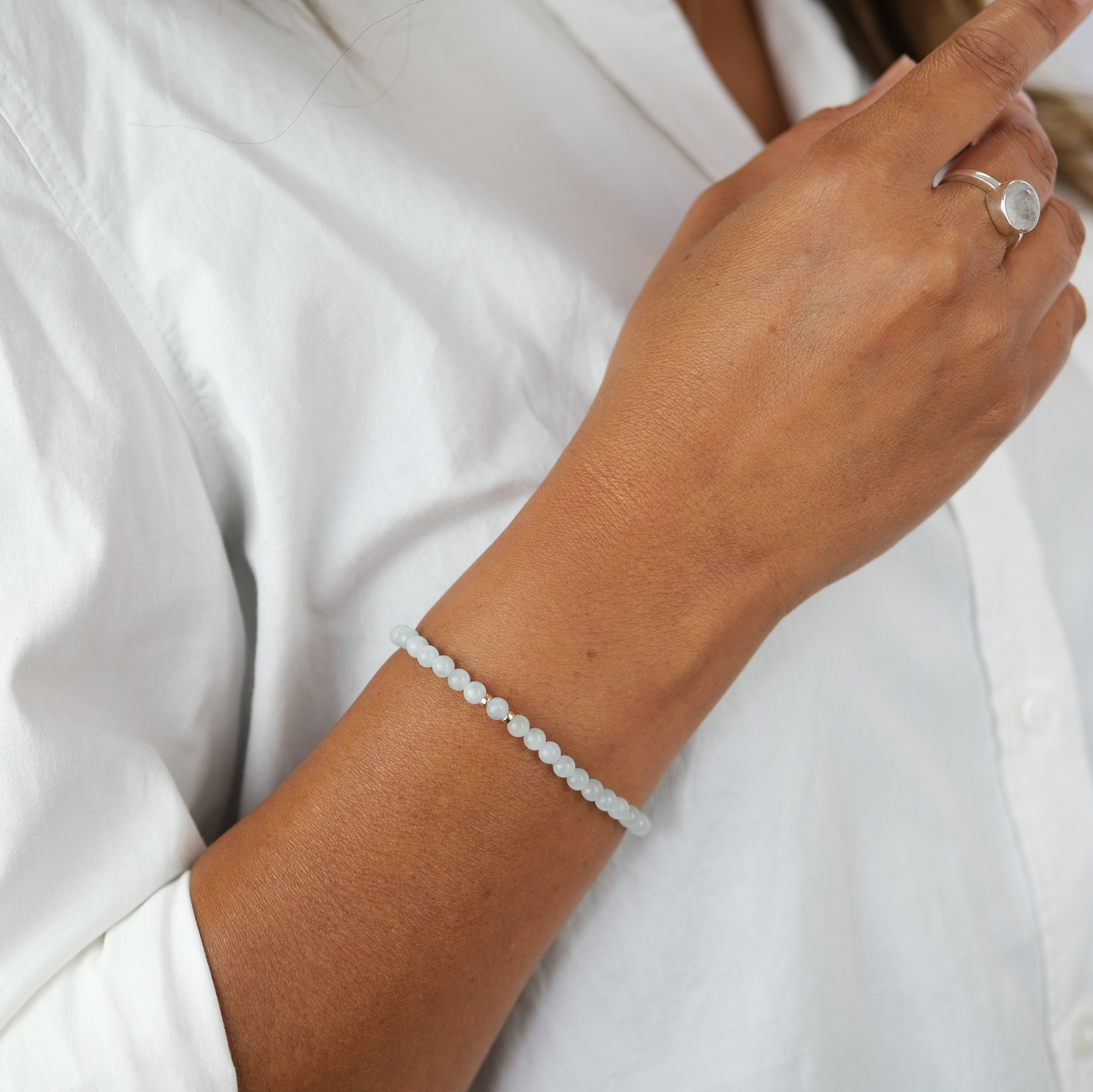 A model wearing Aquamarine gemstone bracelet in 4mm beads with gold accessories