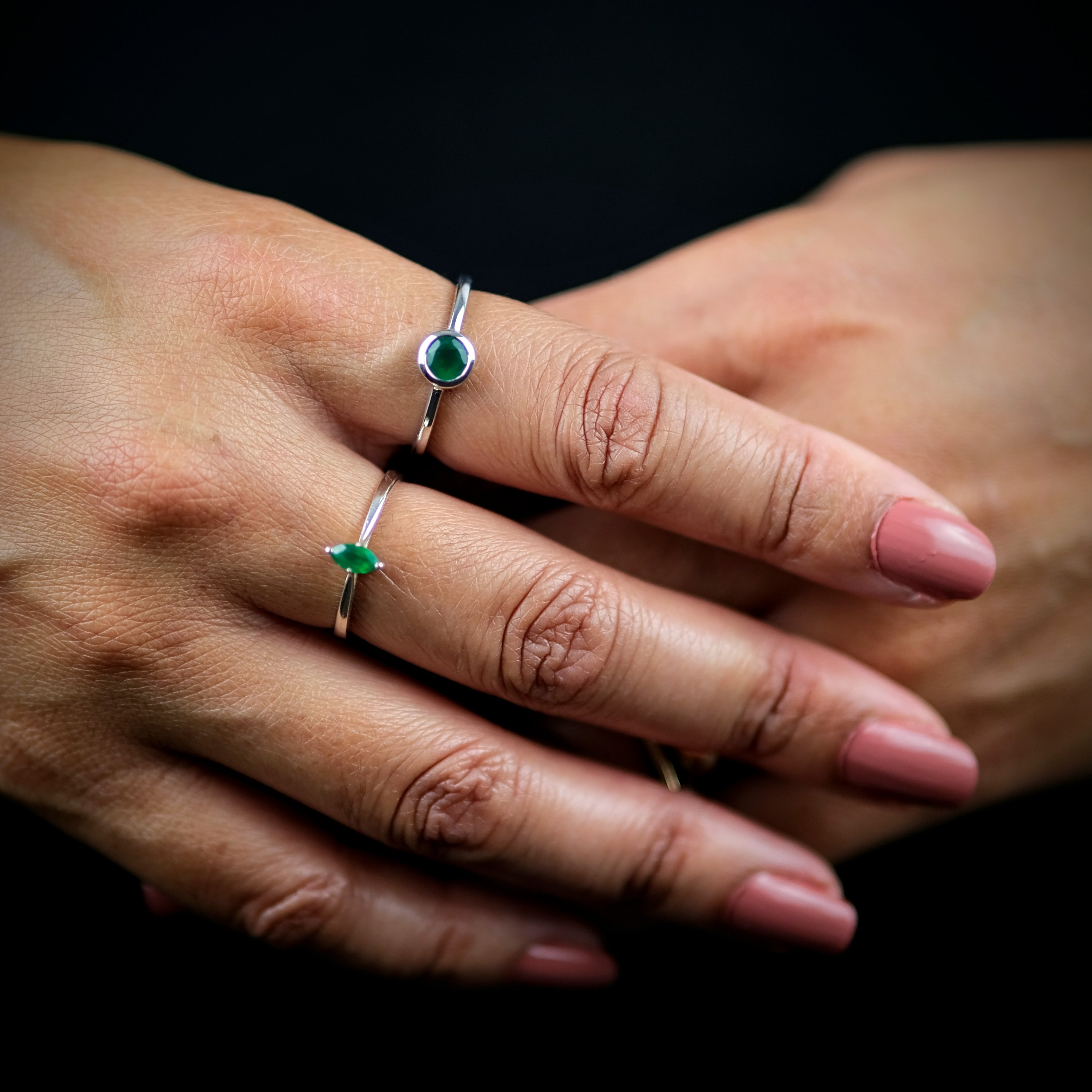 A model wearing two green onyx gemstone rings