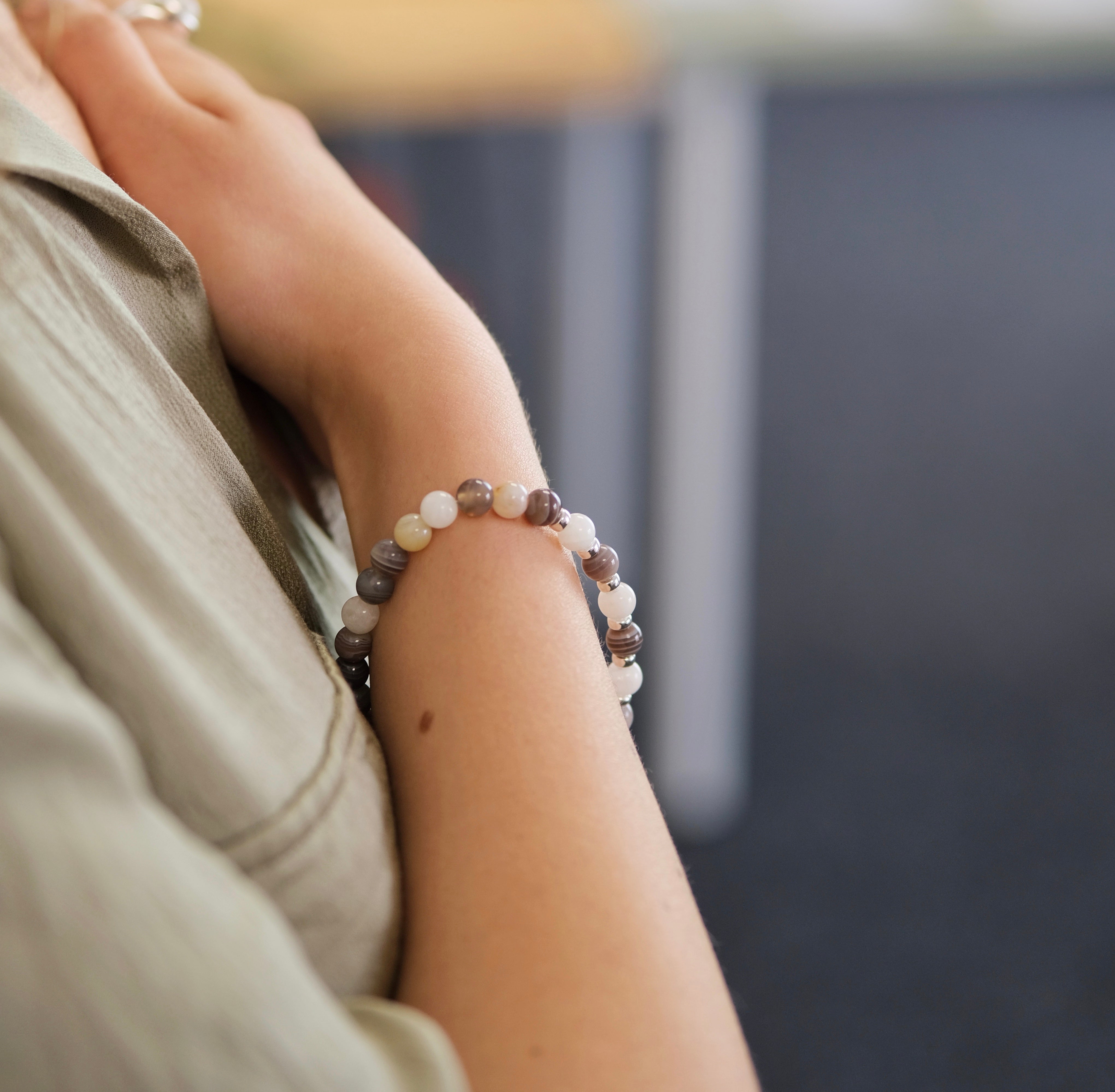 A model wearing Botswana Agate and Moonstone gemstone bracelet in 6mm beads with silver accessories