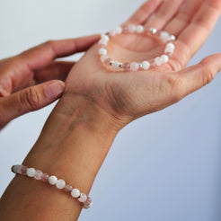 A model wearing A moonstone, strawberry quartz and rose quartz gemstone bracelet in 6mm beads with silver accessories
