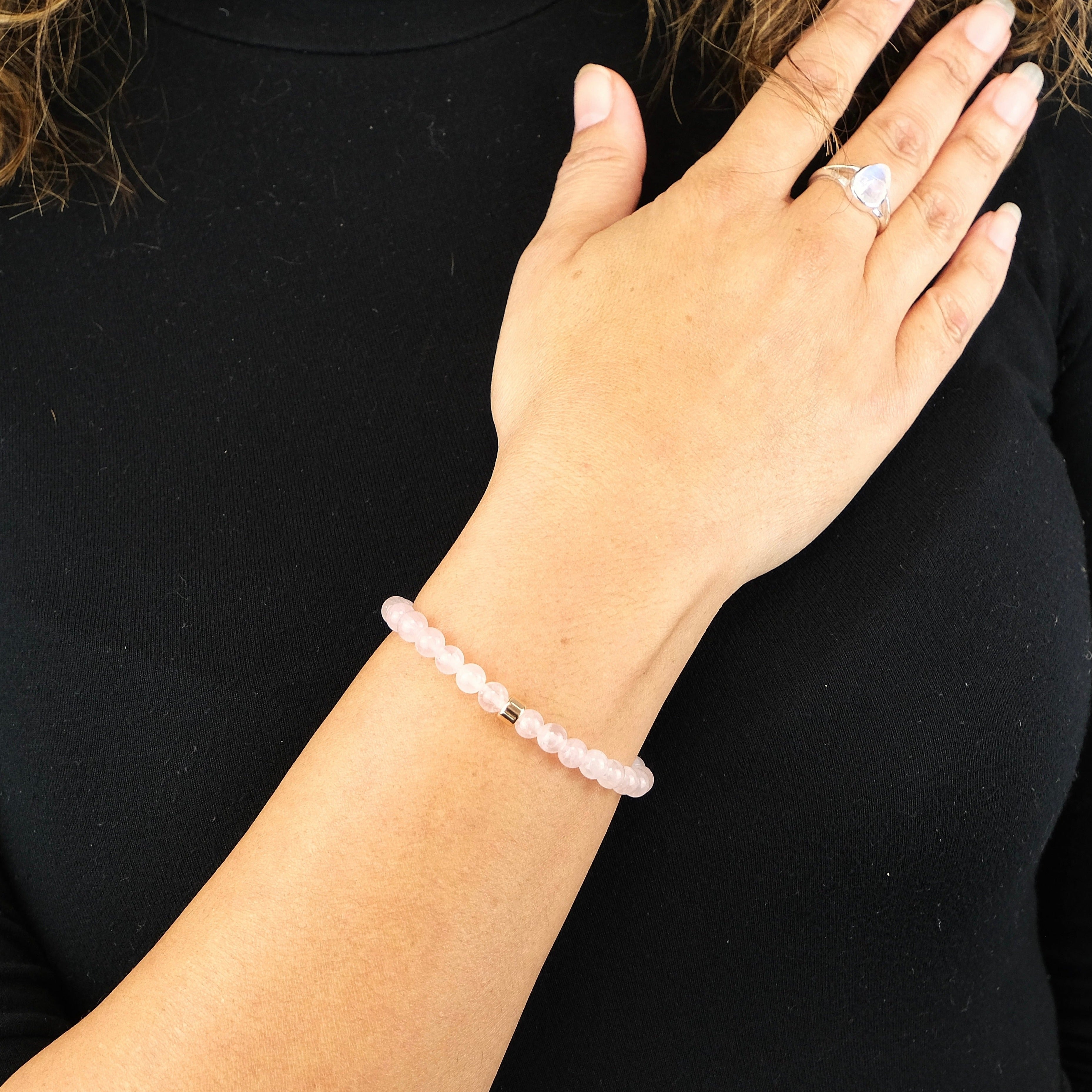 Rose Quartz gemstone bracelet in 6mm beads with 925 sterling silver accent worn on the model's wrist. The model is also wearing a Samayla Jewellery Moonstone teardrop gemstone ring.